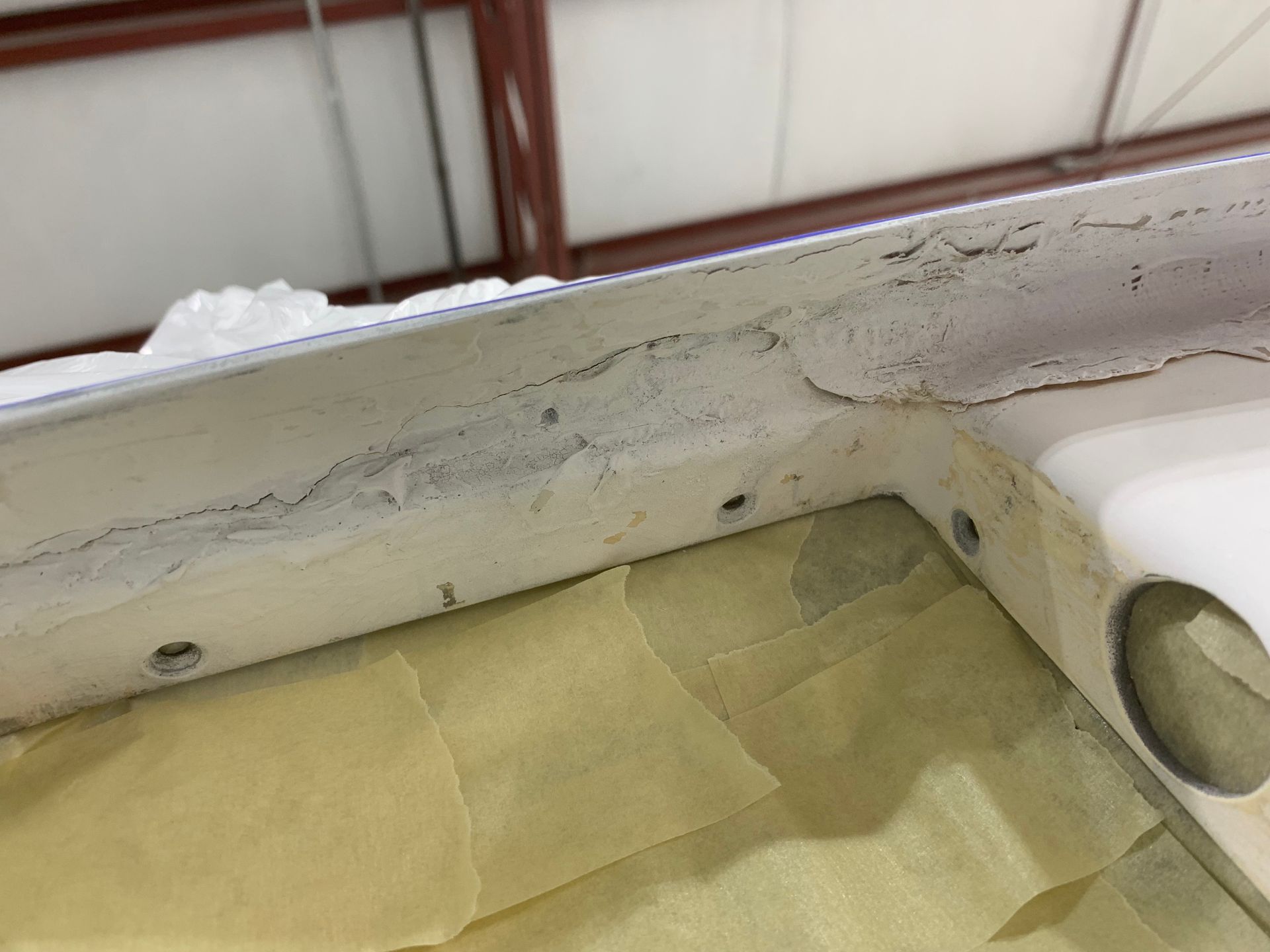 A white piece of metal is sitting on top of a piece of yellow paper.