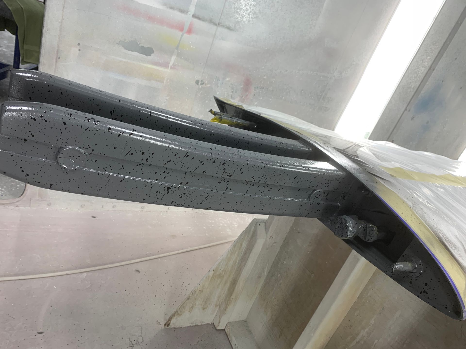 A plane wing is being painted in a paint booth