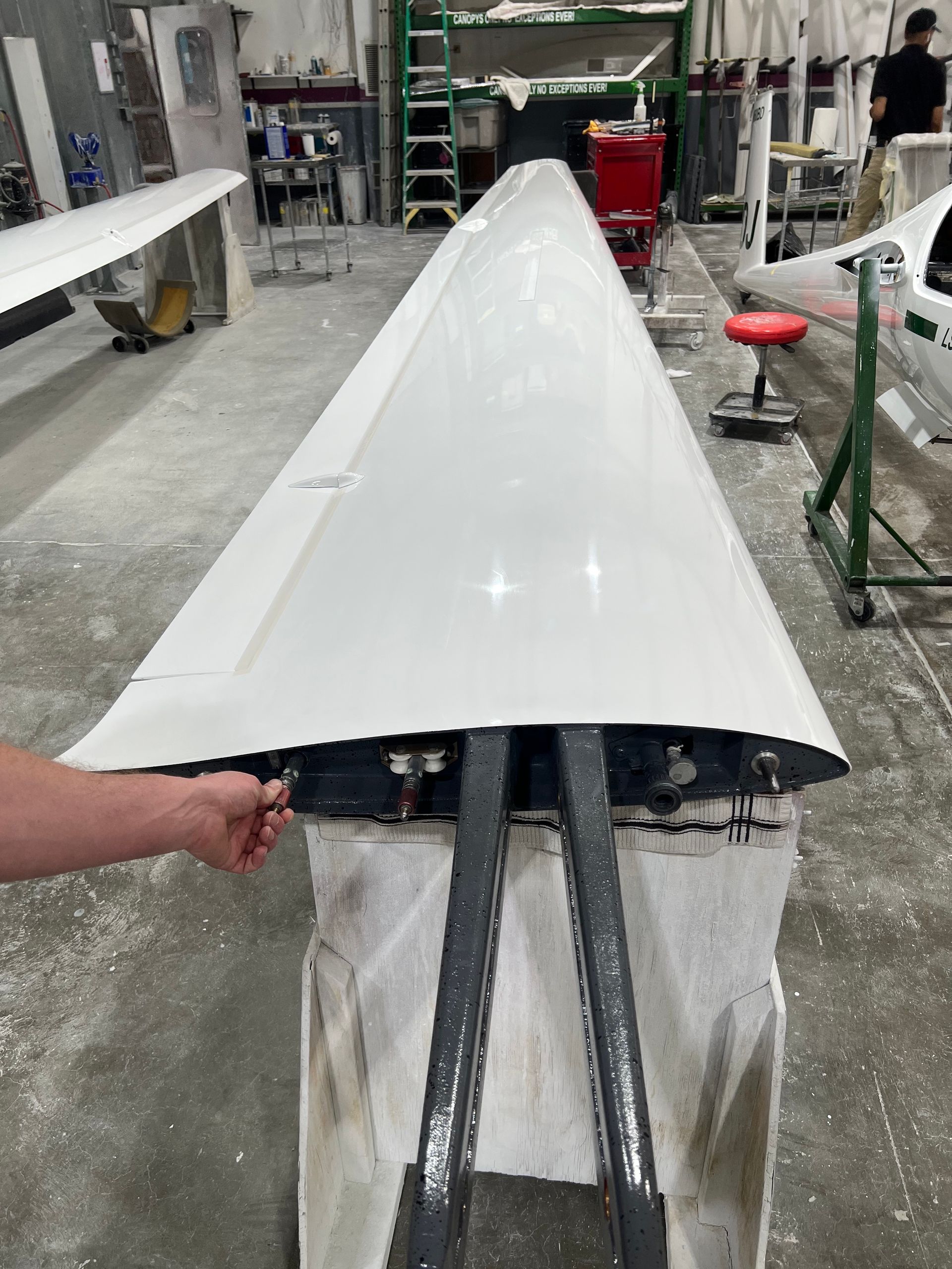 A person is holding a white wing in a factory.