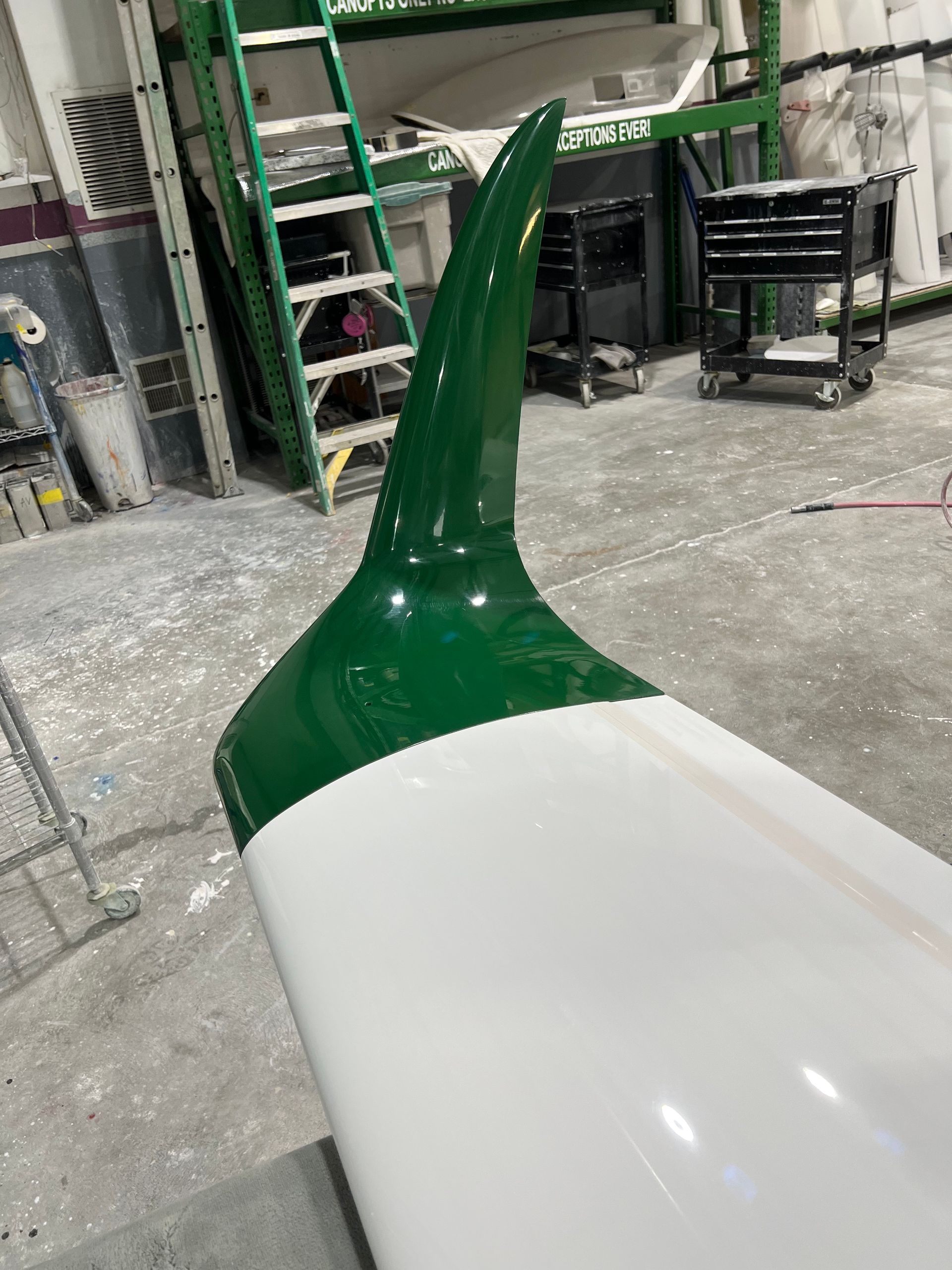 A green and white object is sitting in a garage.