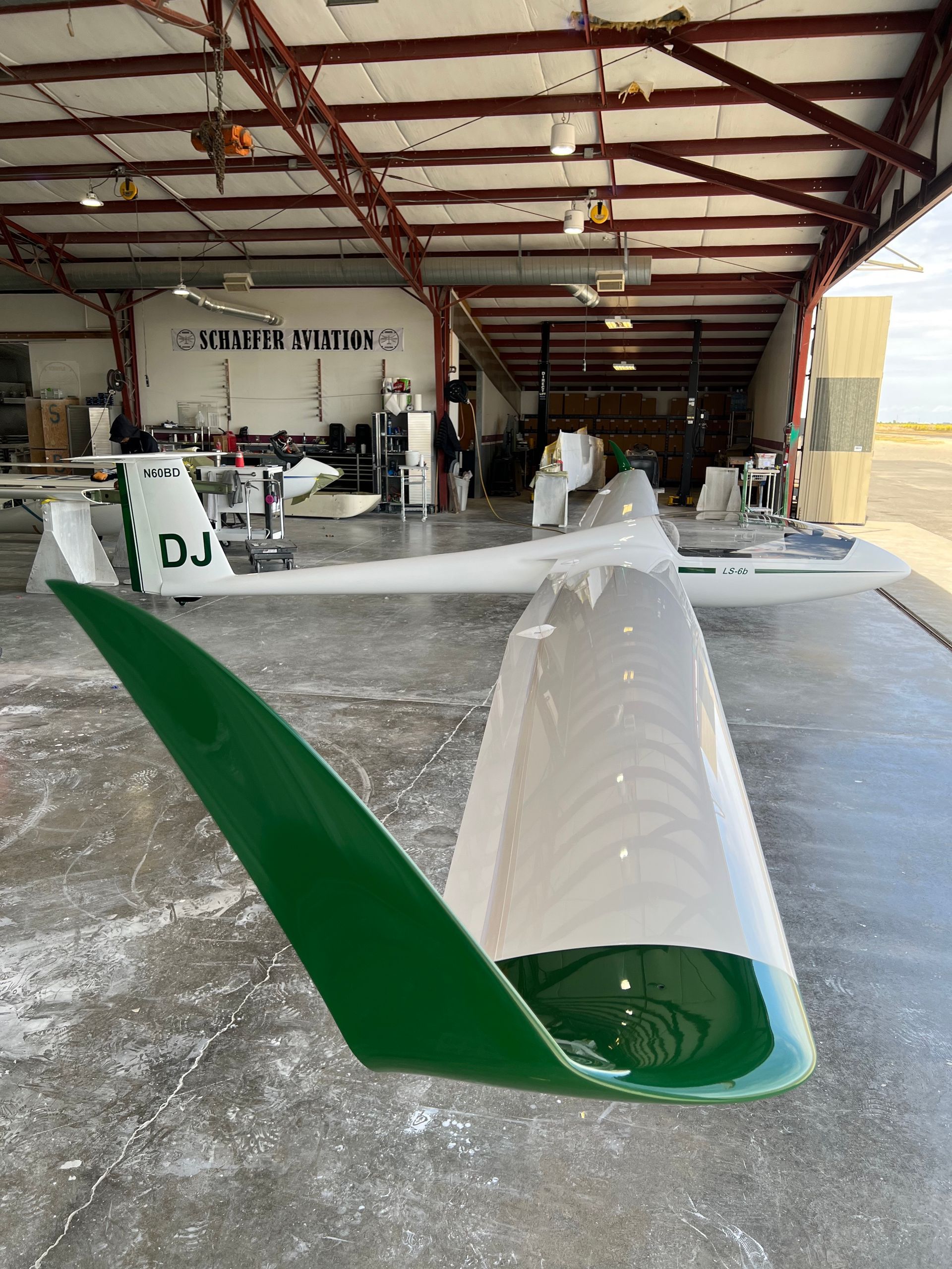 A white plane with dj on the side is parked in a hangar