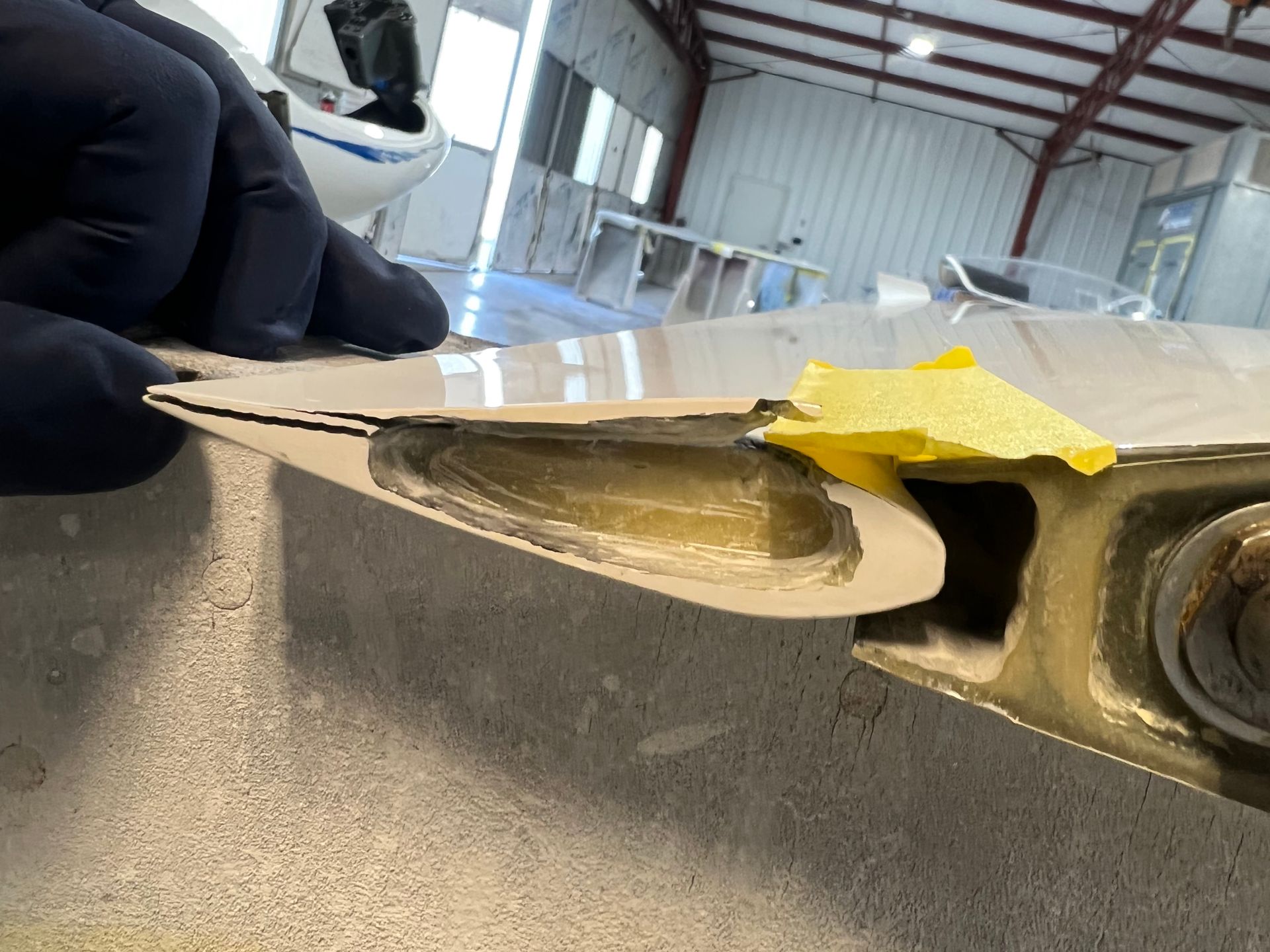 A person is holding a piece of metal with a yellow piece of tape on it.