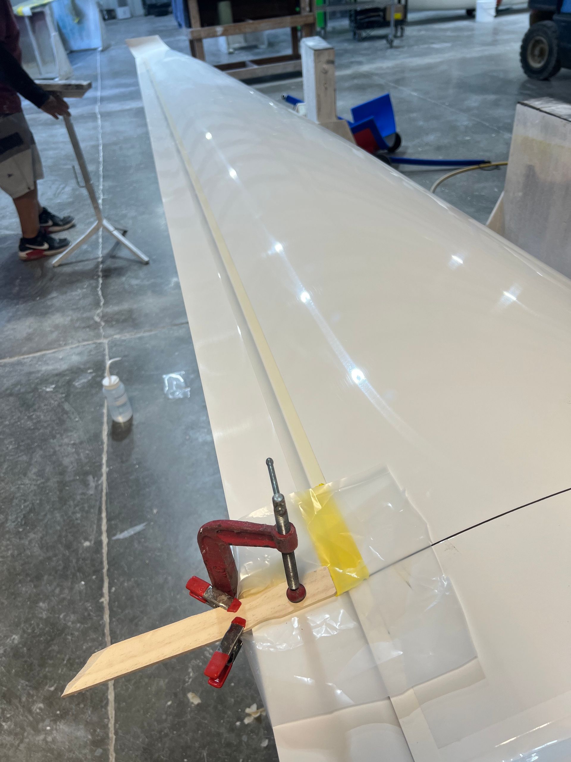 A person is working on a plane wing with a clamp on it
