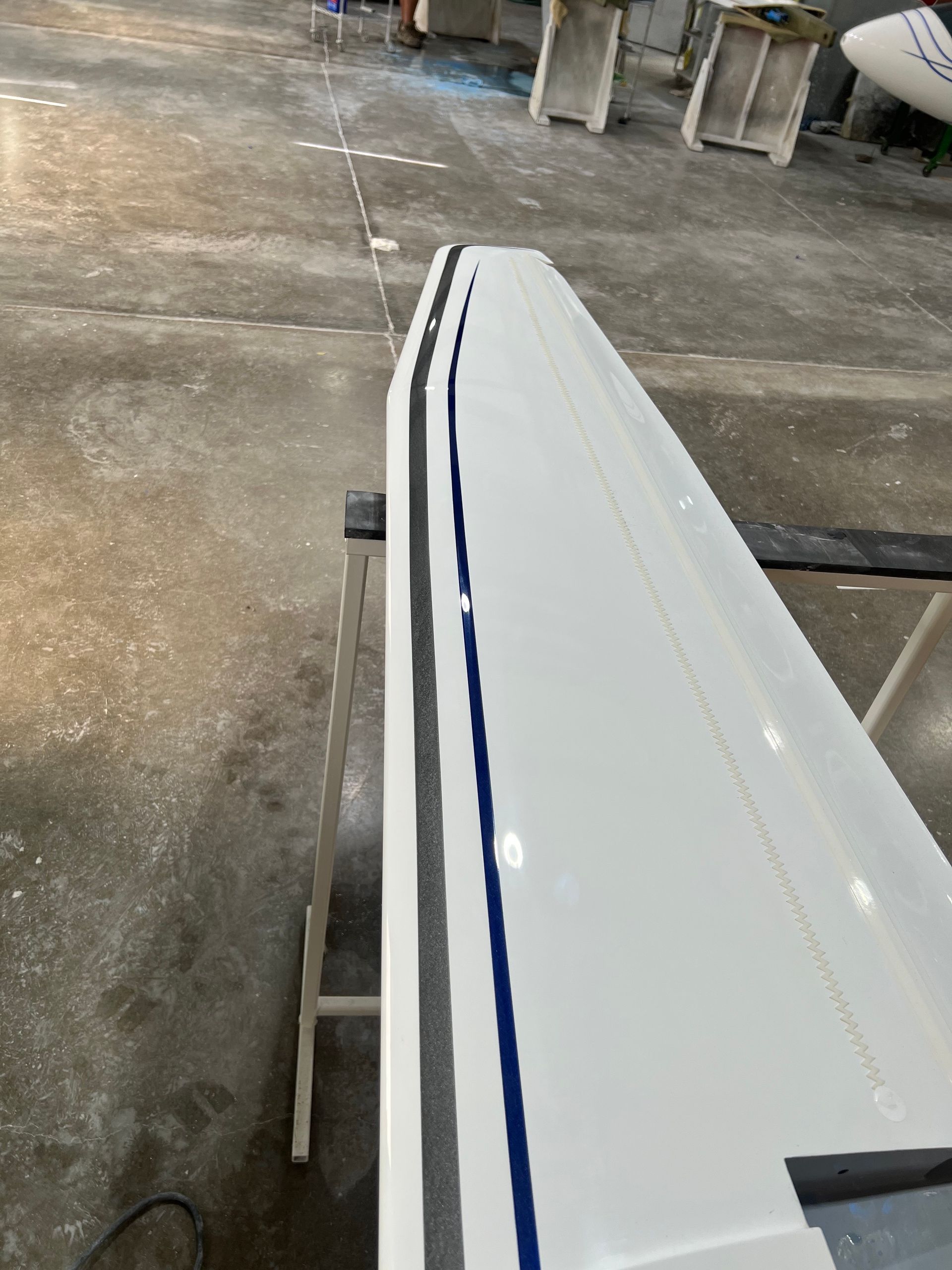 A white boat is sitting on a table in a warehouse.