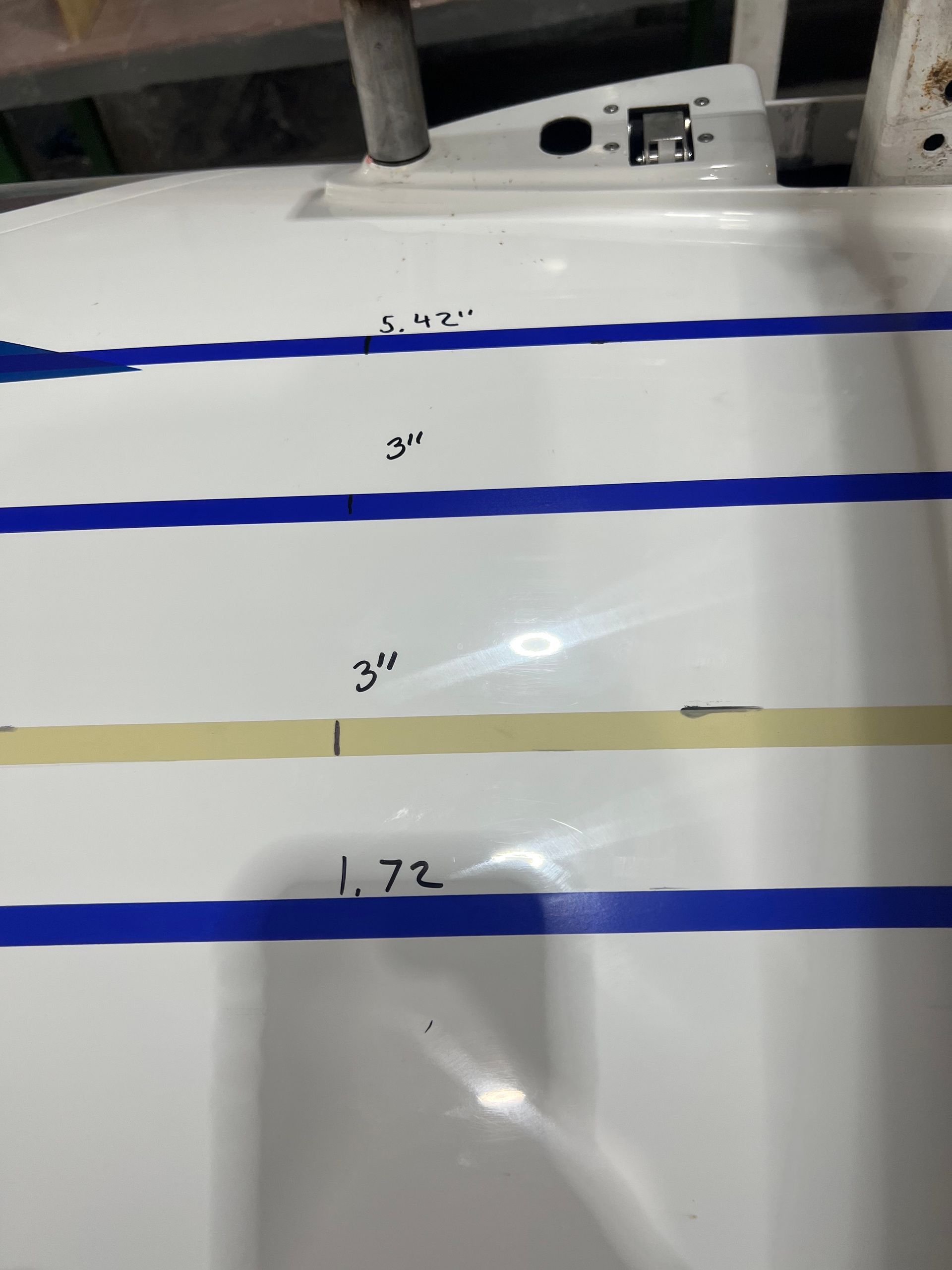 A white surface with blue tape and measurements on it