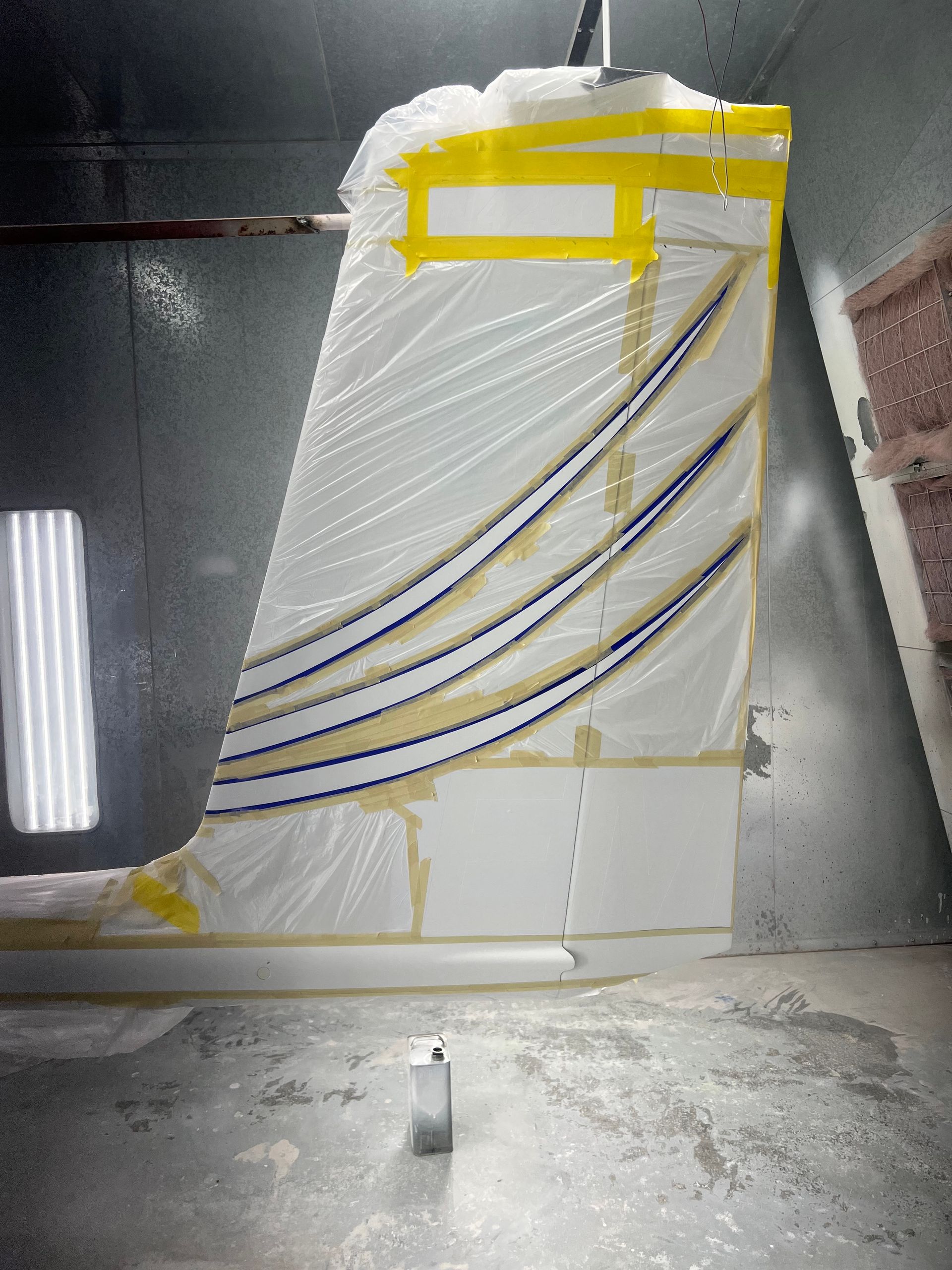 A wing of an airplane being painted in a paint booth