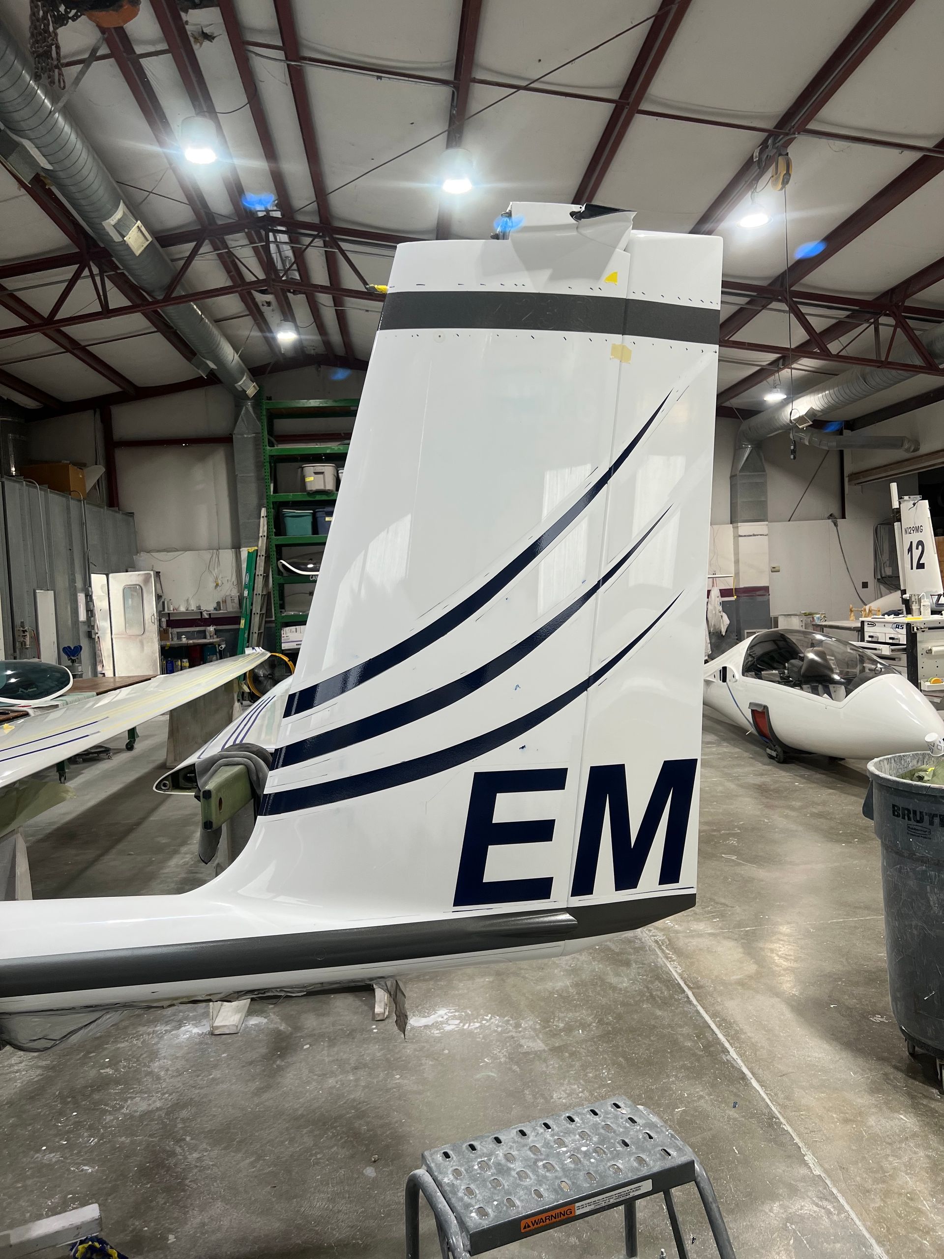 A white plane with the letters em on the tail is in a hangar.