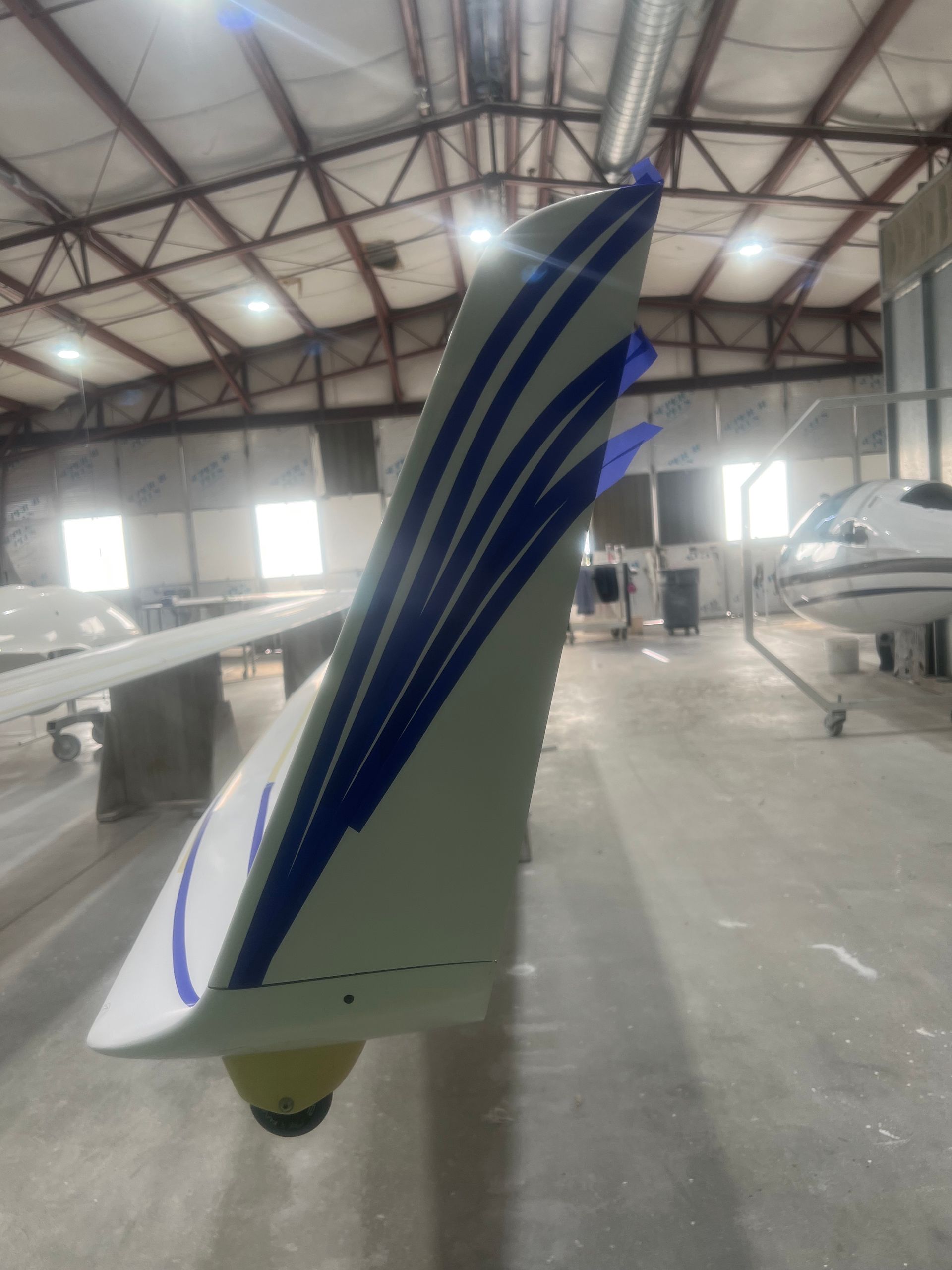 A white plane with blue stripes is sitting in a hangar