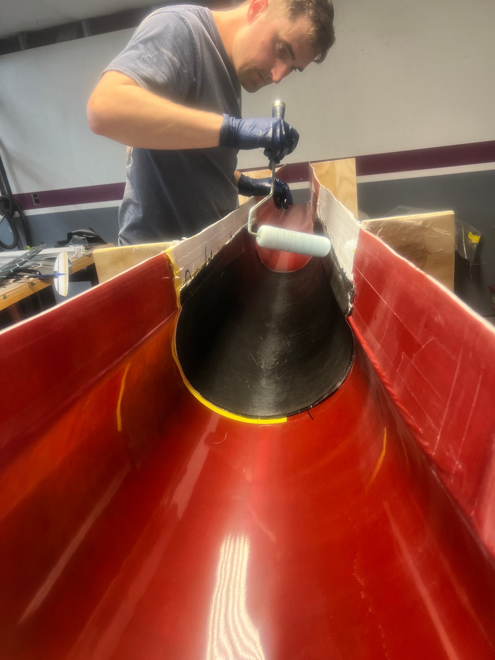 A man is painting a red pipe with a roller.