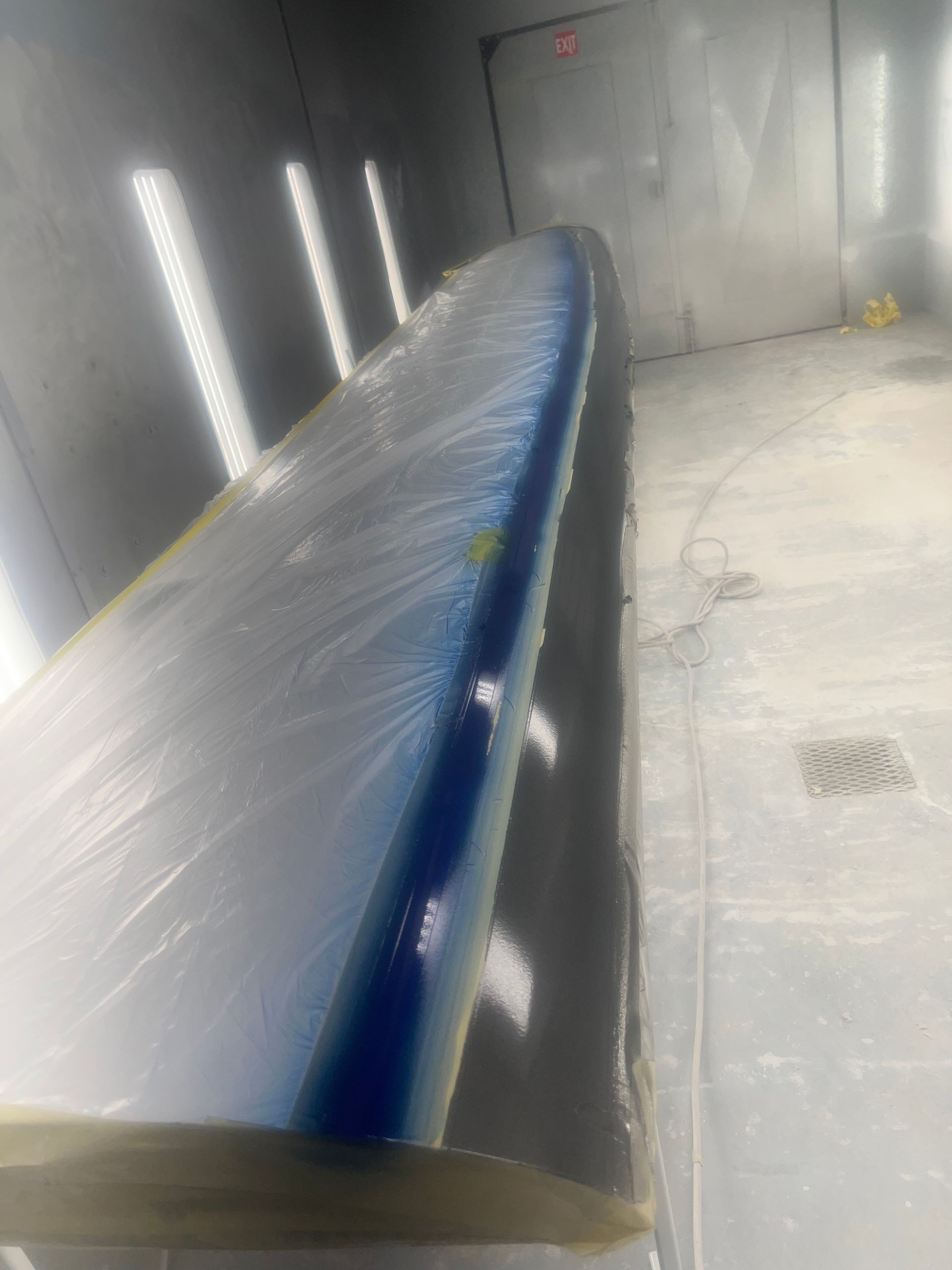 A boat is being painted in a paint booth.