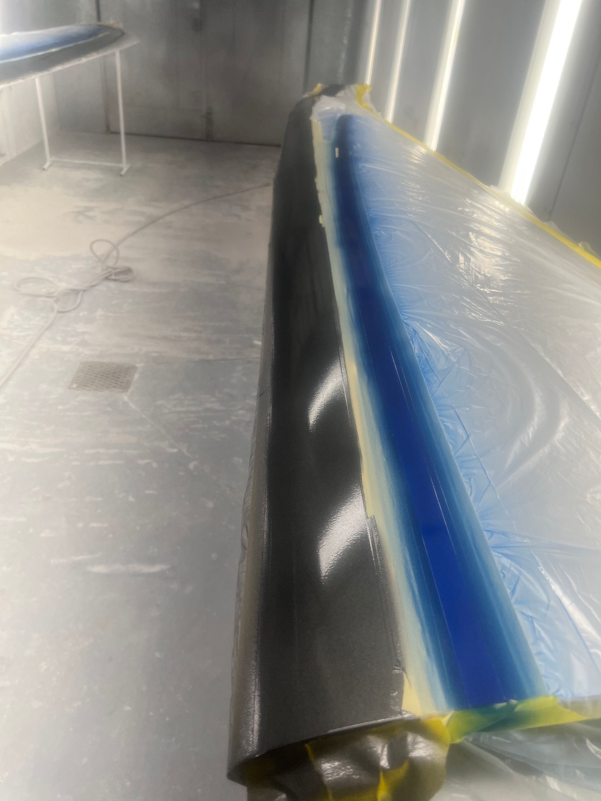 A car is being painted in a paint booth.