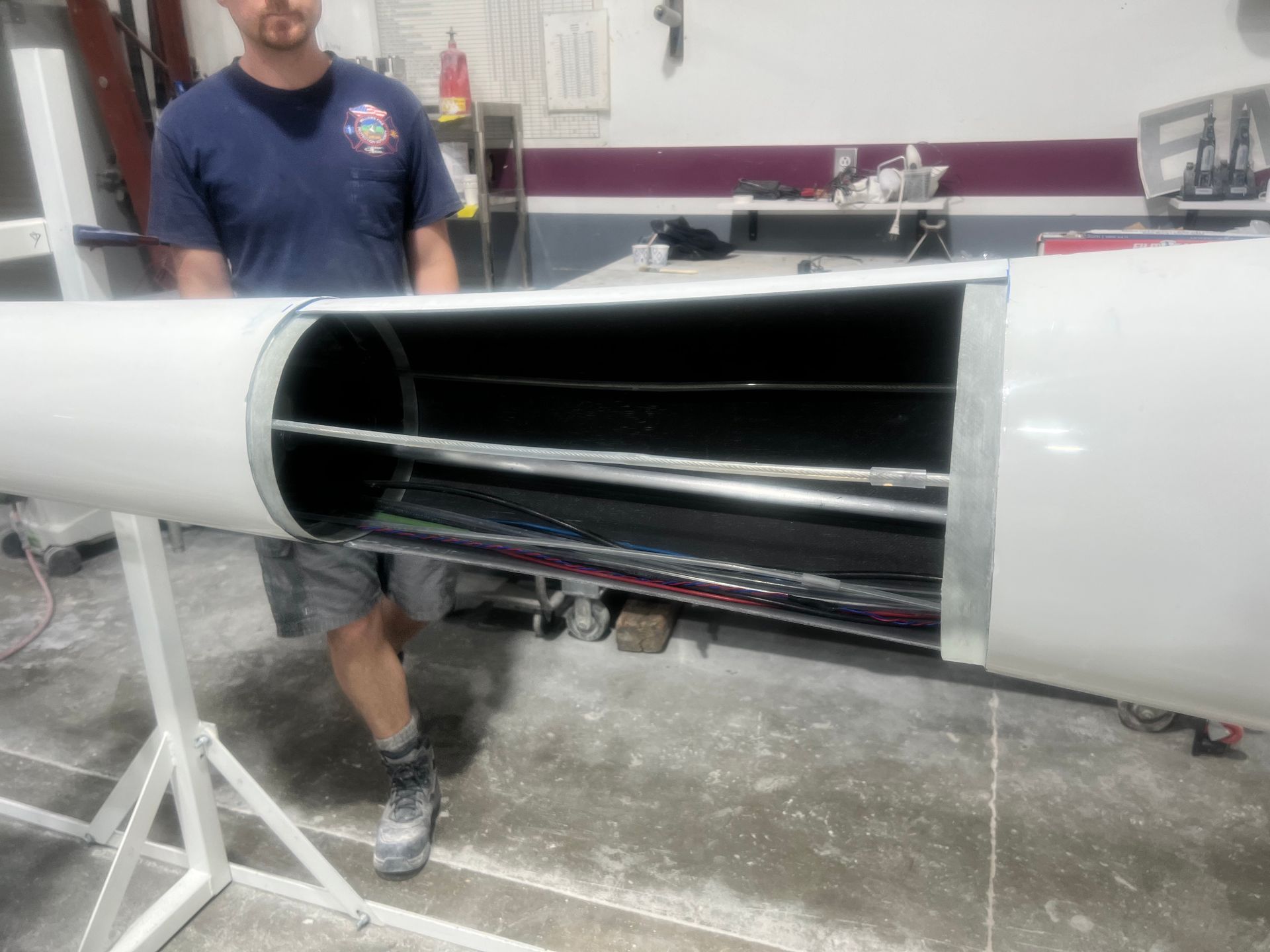 A man in a blue shirt is standing next to a large white pipe
