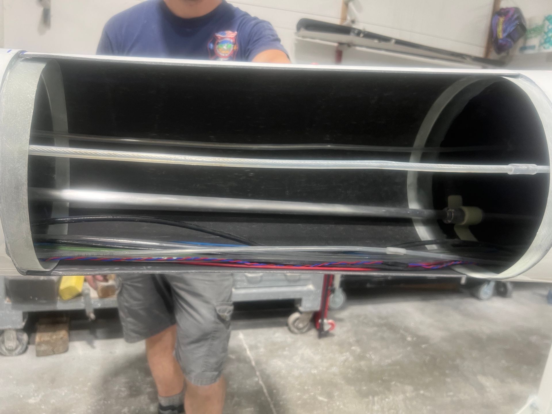 A man in a blue shirt is holding a large metal tube