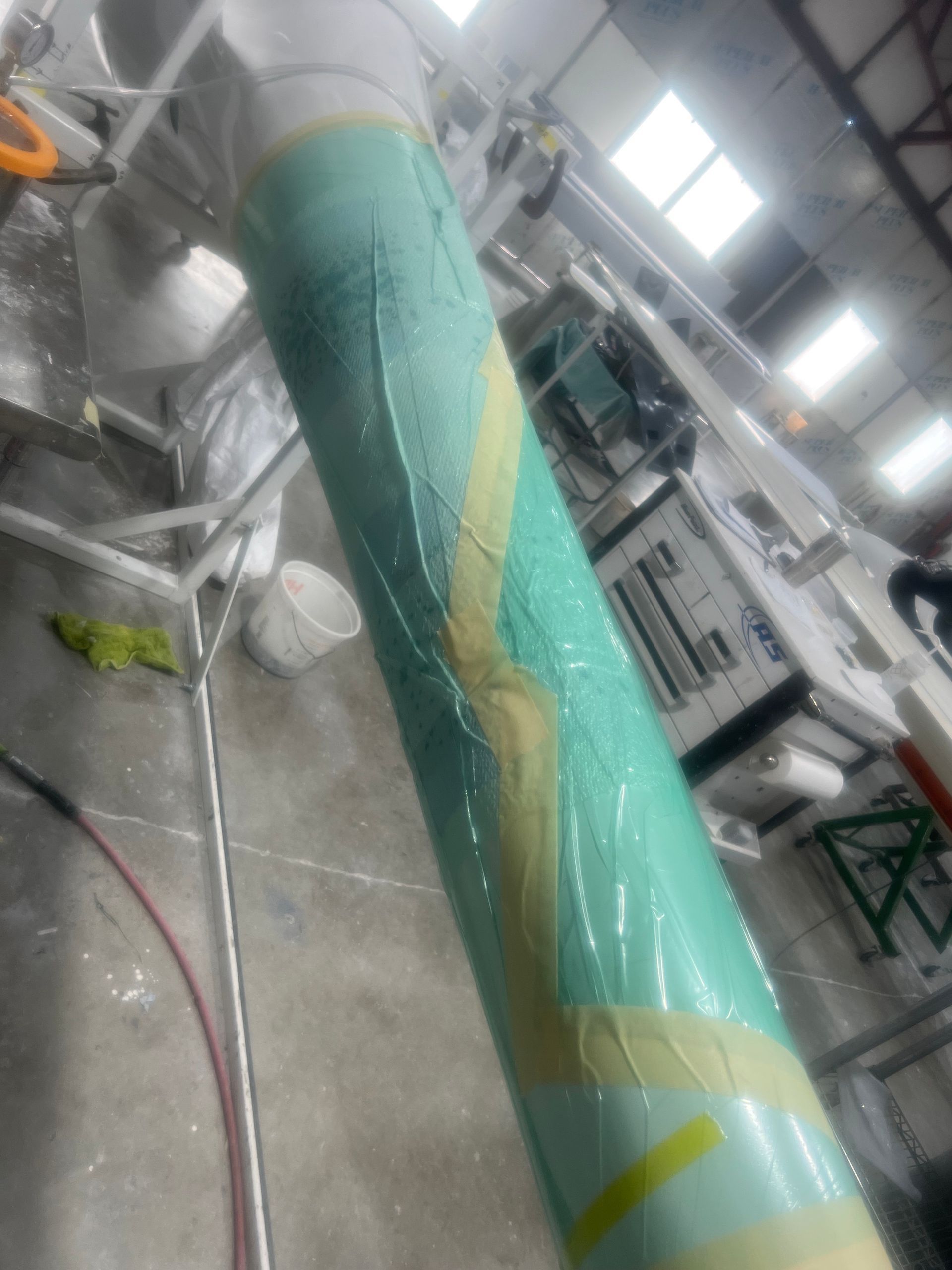 A green pipe is being painted in a factory