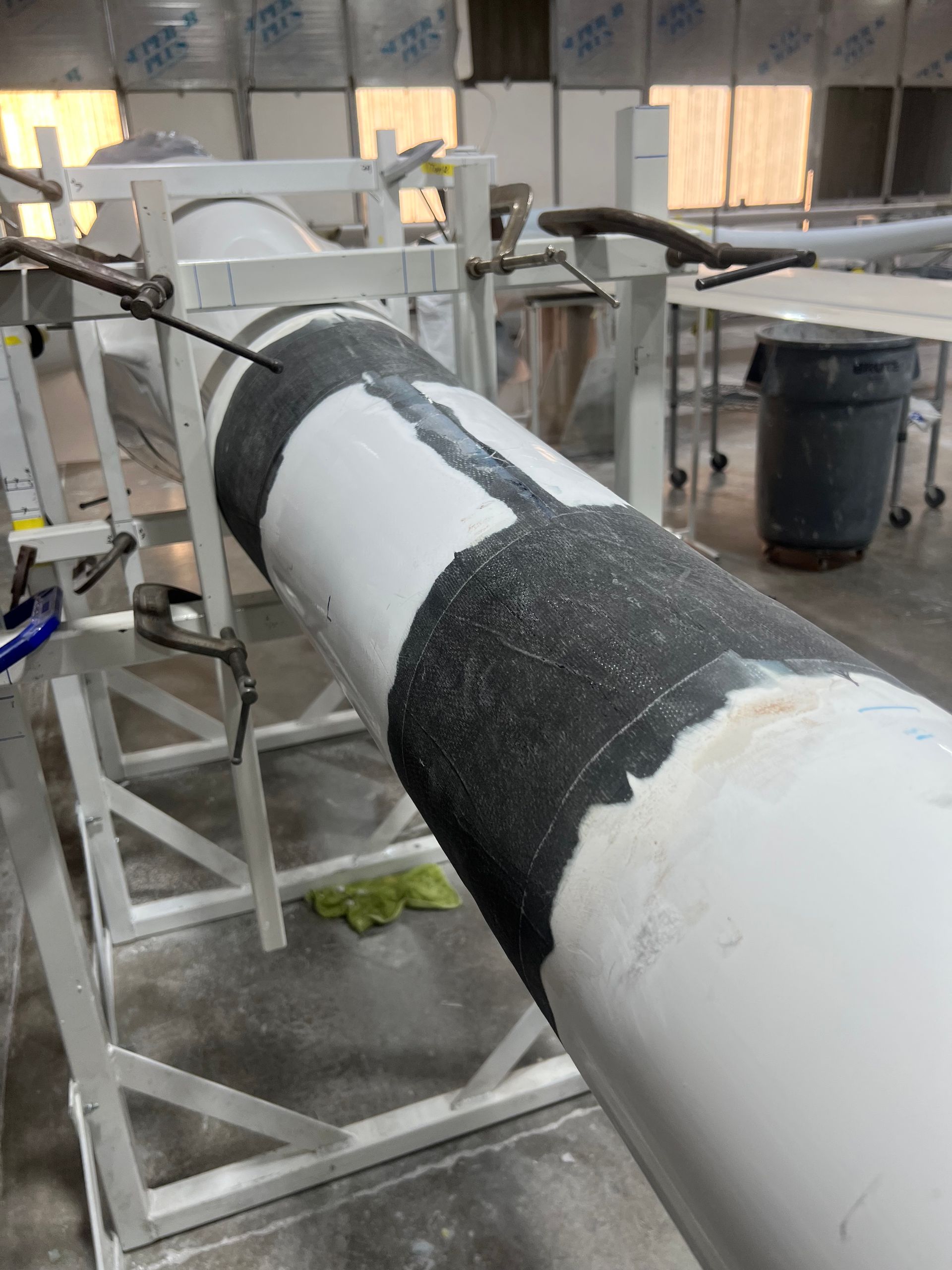 A white pipe with a black stripe on it is sitting on a stand in a room.