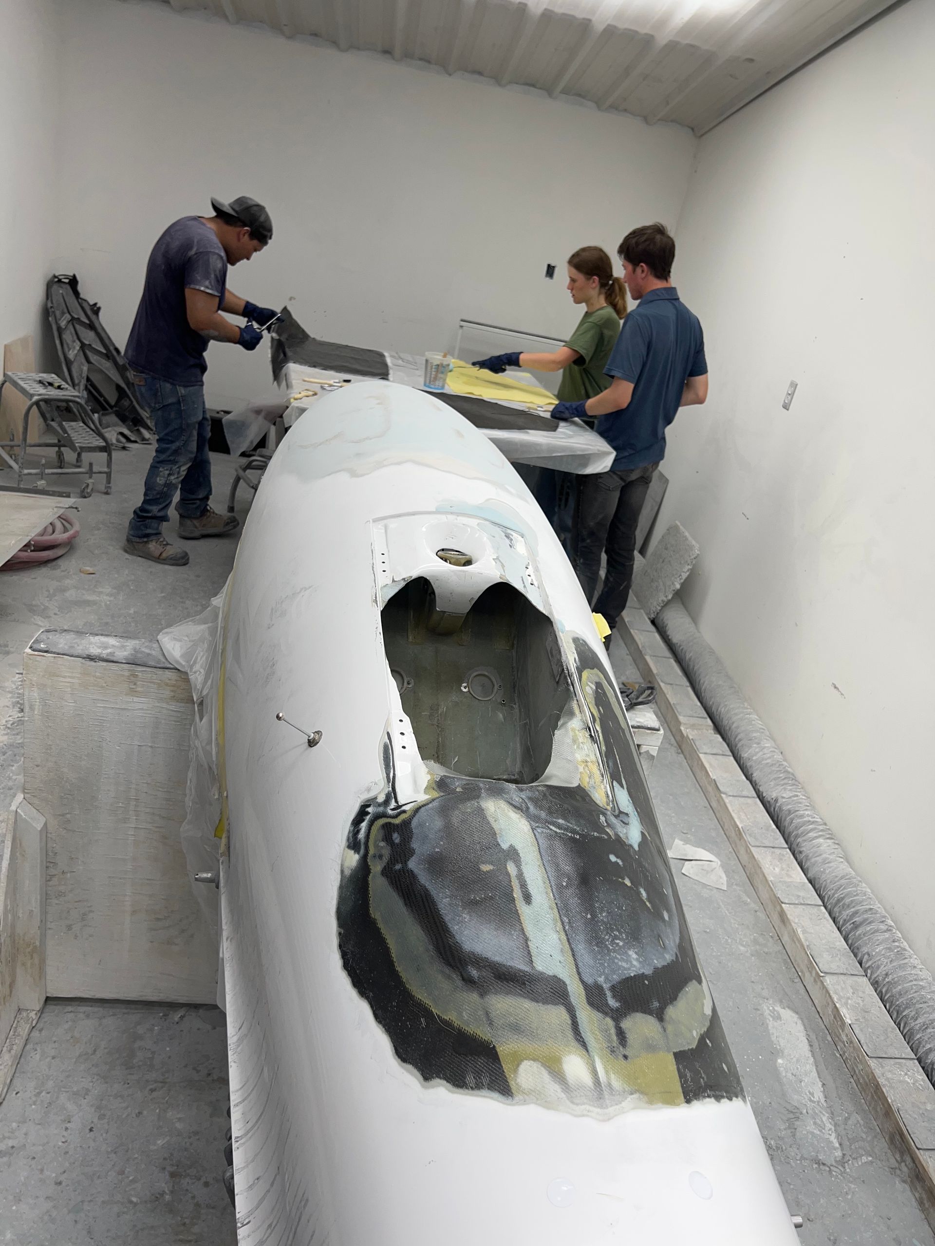 A group of people are working on a boat in a garage