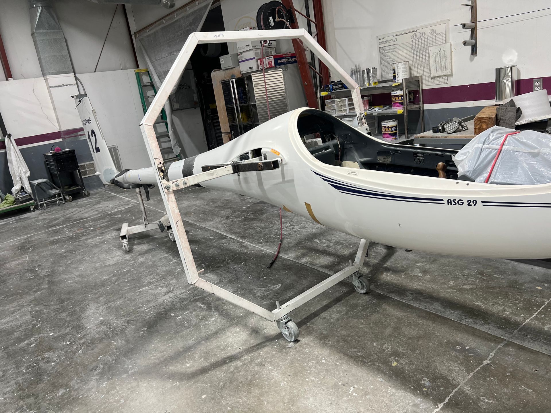 A white plane is sitting on a cart in a garage.