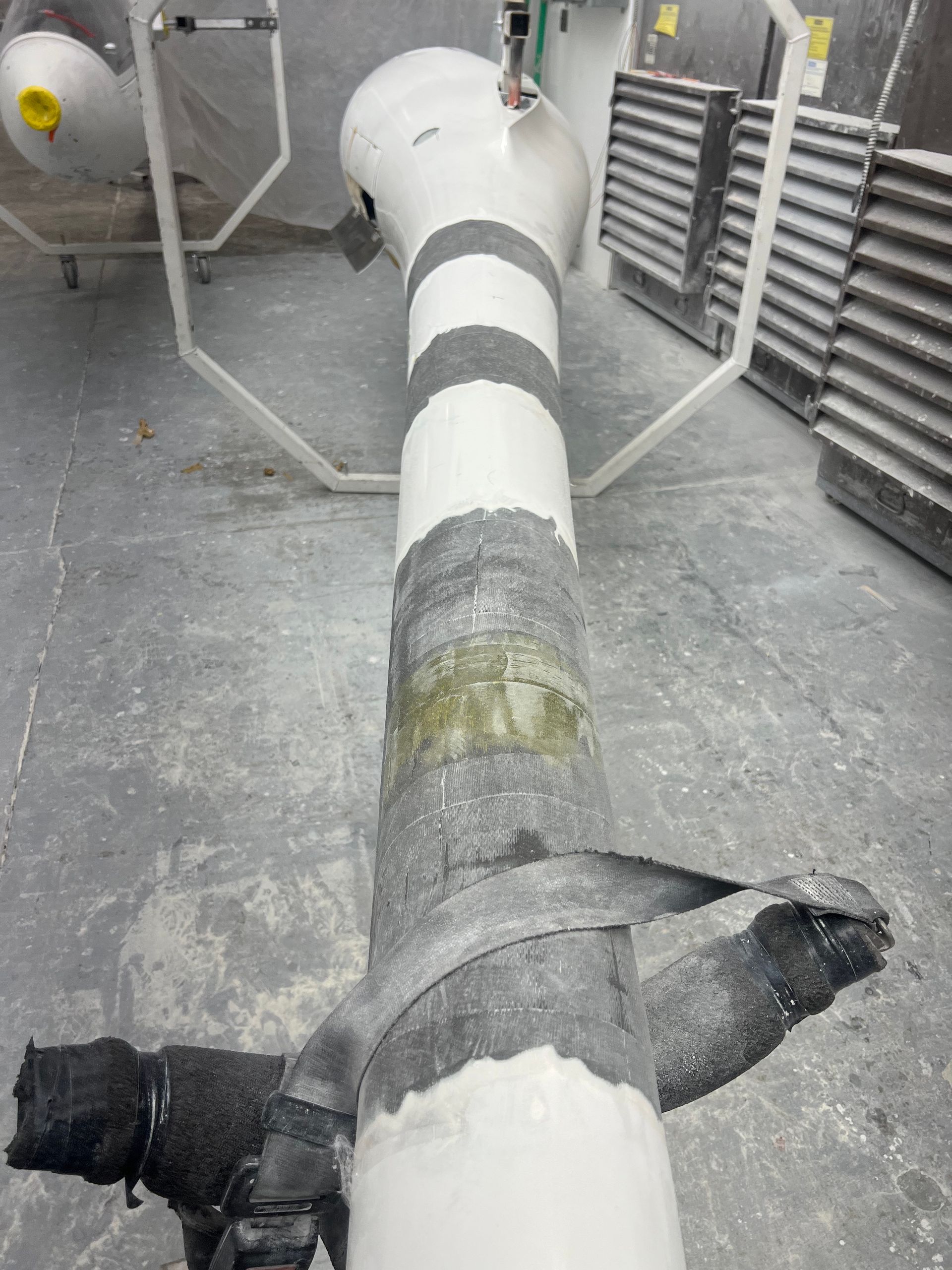 A white pipe with black stripes is sitting on a concrete floor