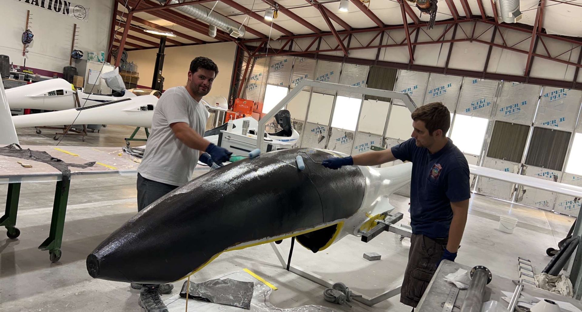 Two men are working on an airplane in a factory.
