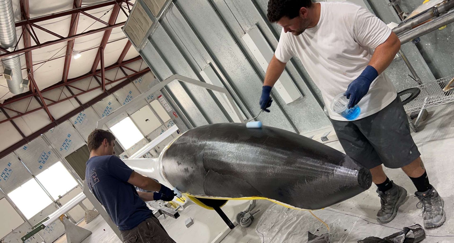 Two men are working on a large object in a room.