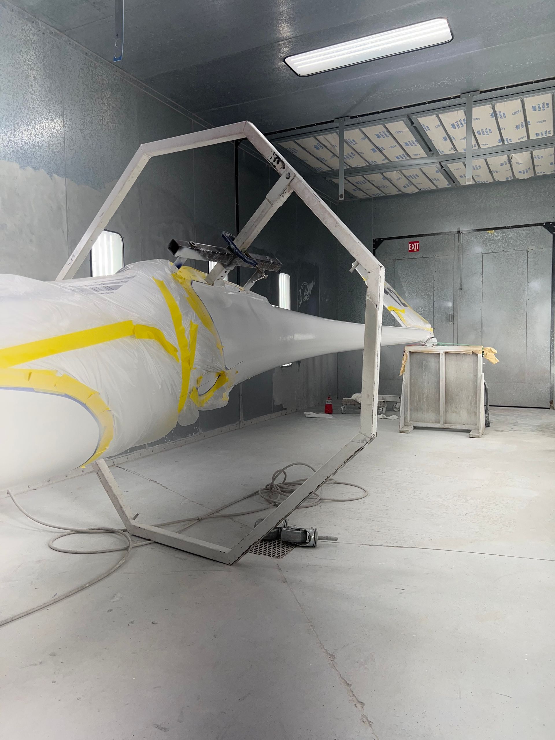 A helicopter is being painted in a paint booth