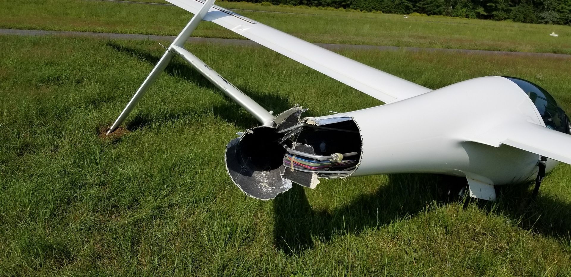 A small white plane is sitting on top of a lush green field.