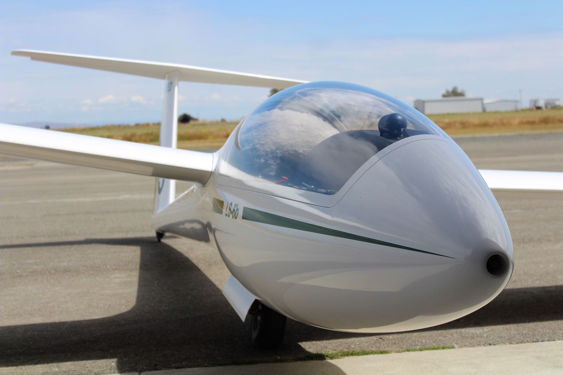 A small white plane with a clear cockpit is parked on a runway