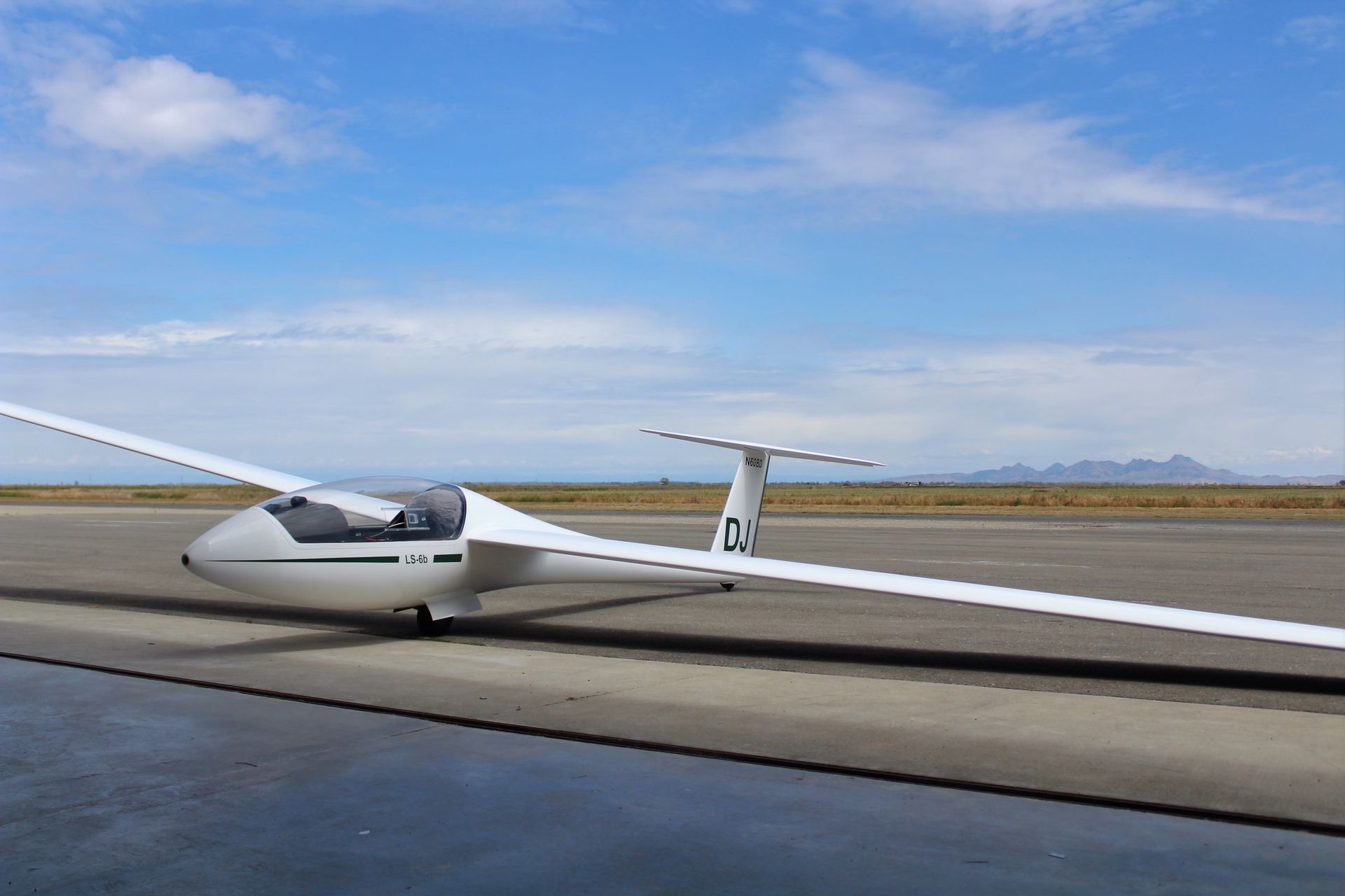 A glider with the number d3 on the tail is parked on a runway