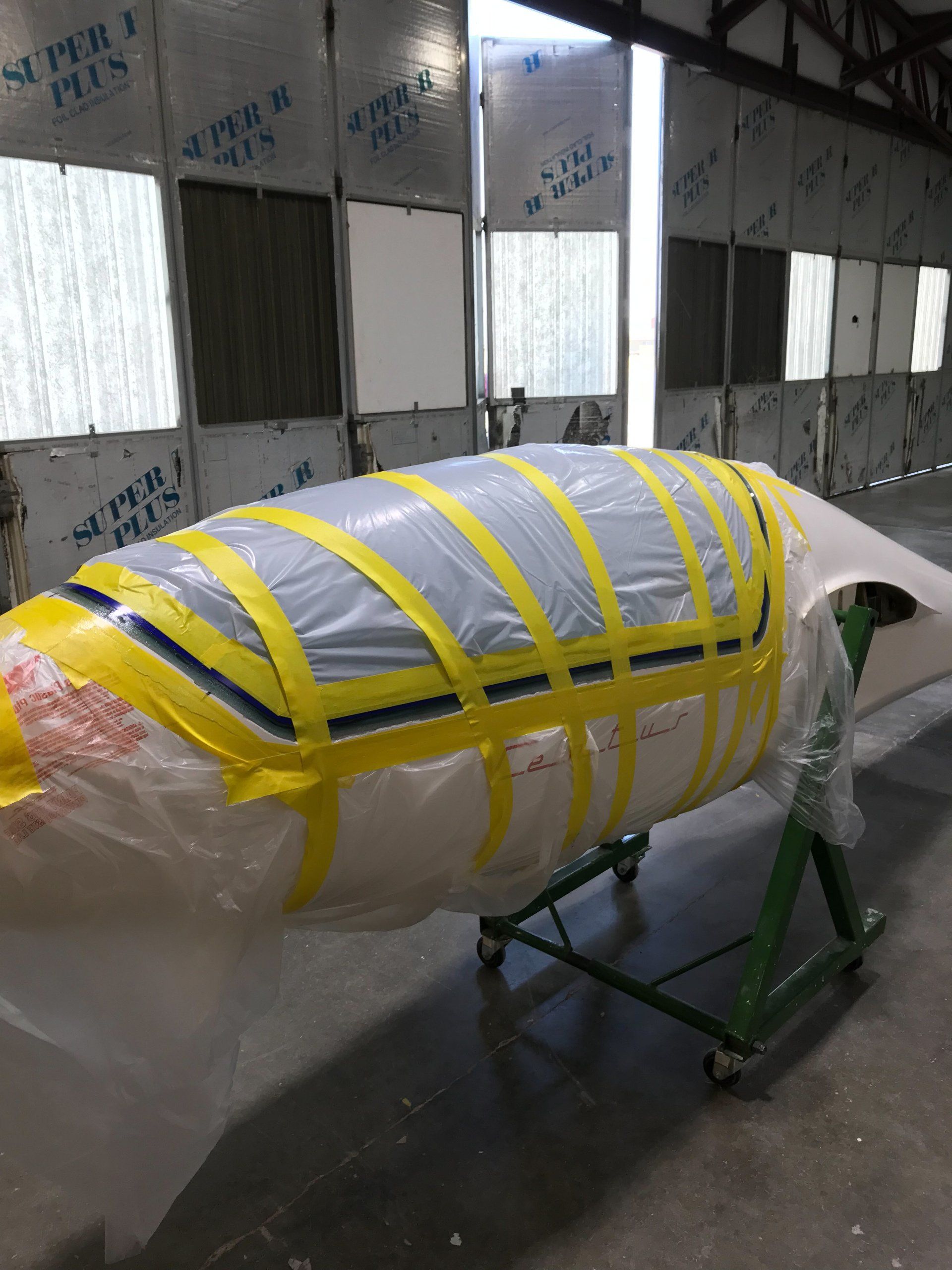 A whale is wrapped in plastic and tape in a warehouse