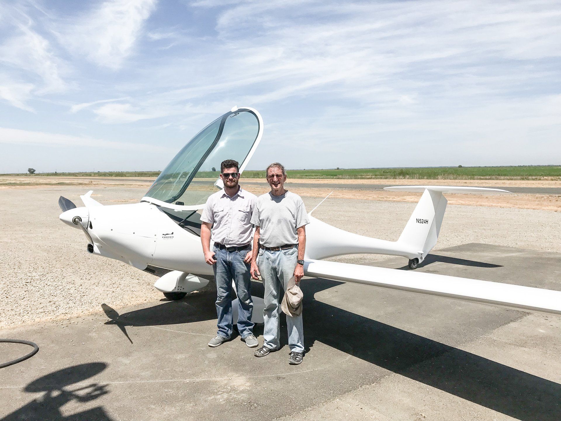 Two men are standing in front of a small plane