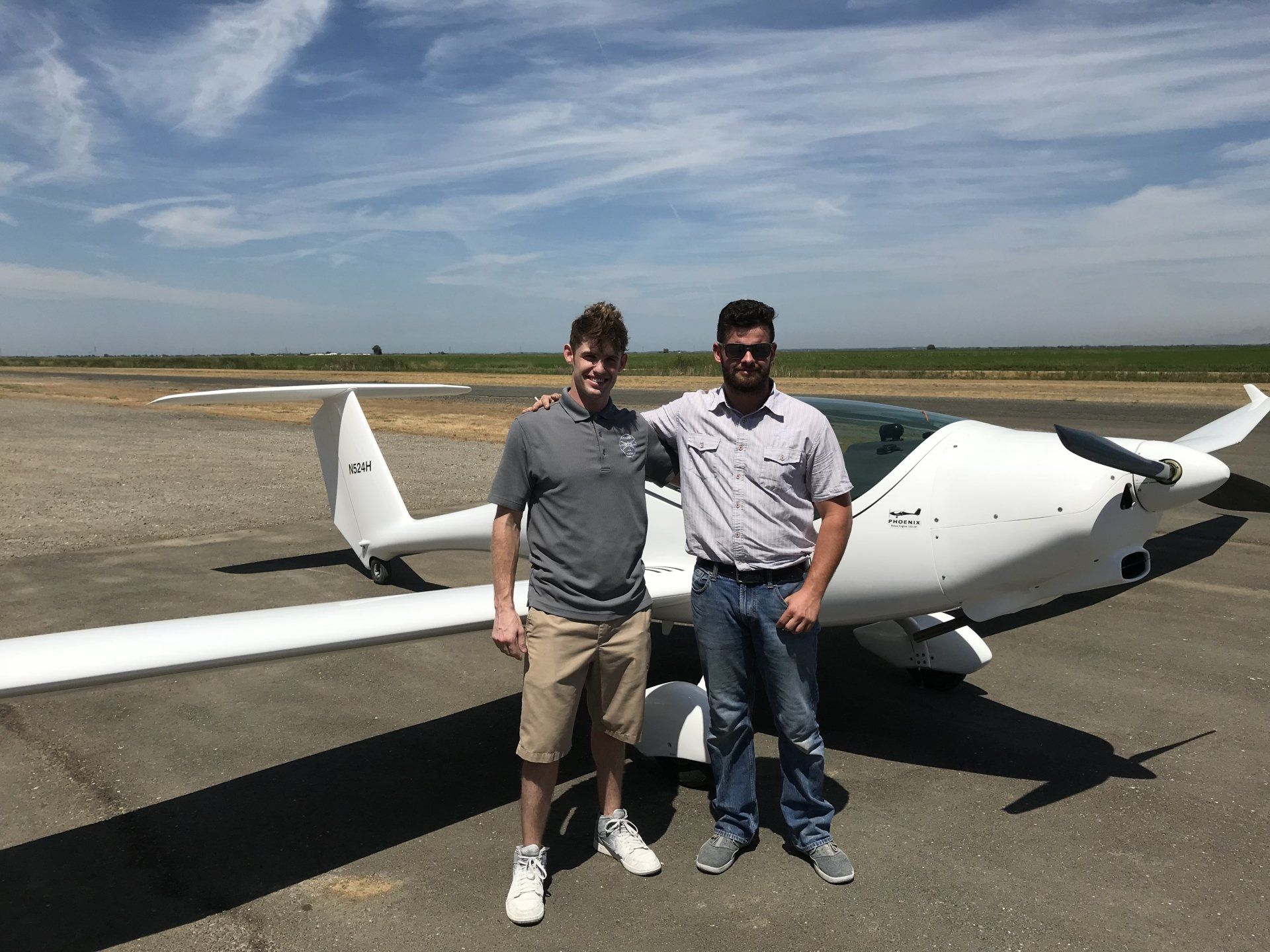 Two men are standing in front of a small plane on a runway.