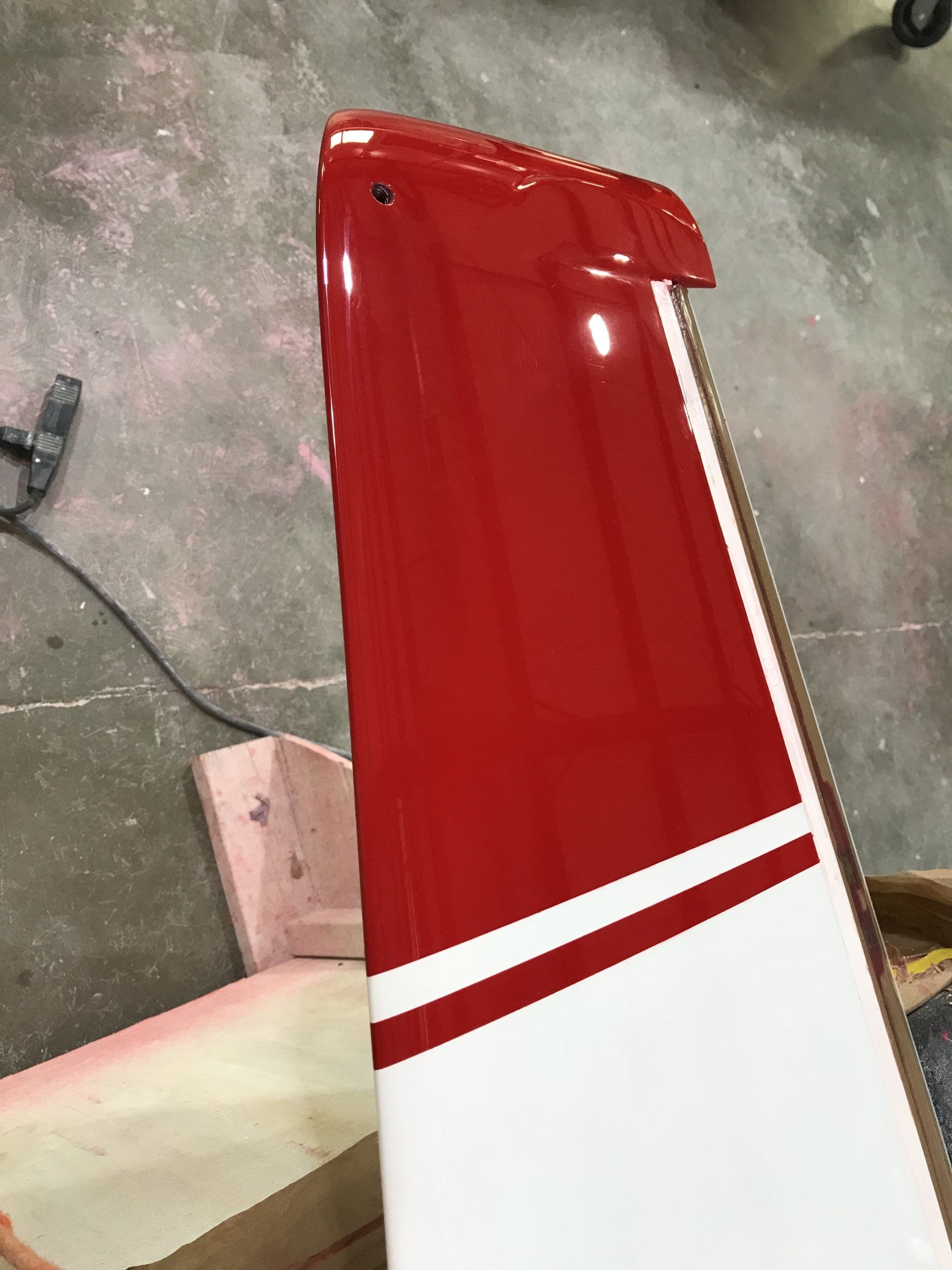 A red and white plane wing is sitting on the ground