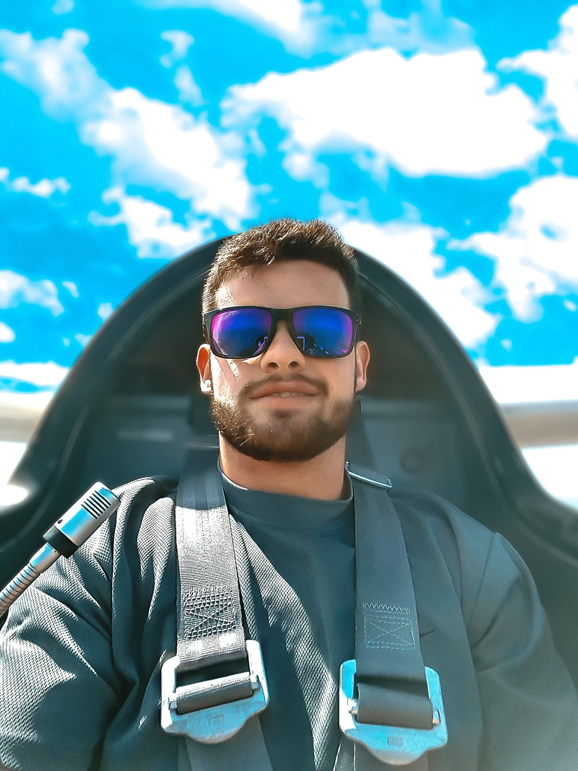 A man wearing sunglasses is sitting in a plane