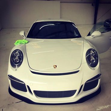 A white porsche is parked in a garage with the door open