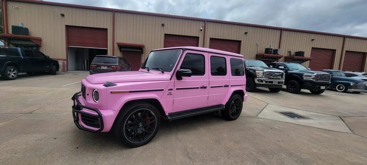 A pink jeep is parked in front of a building.