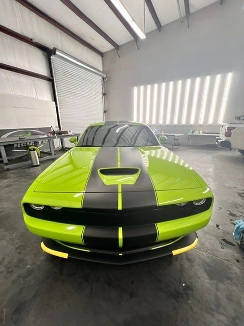 A green car with black stripes is parked in a garage