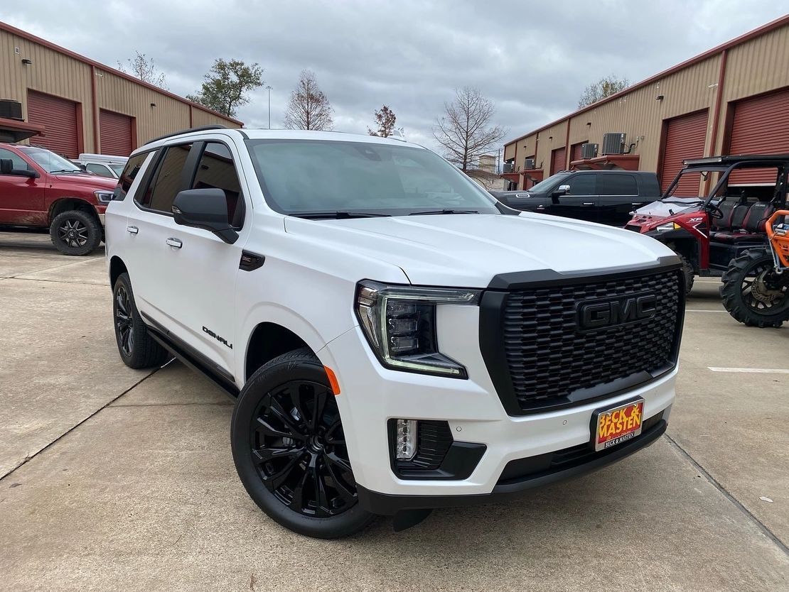 A white gmc yukon is parked in a parking lot.