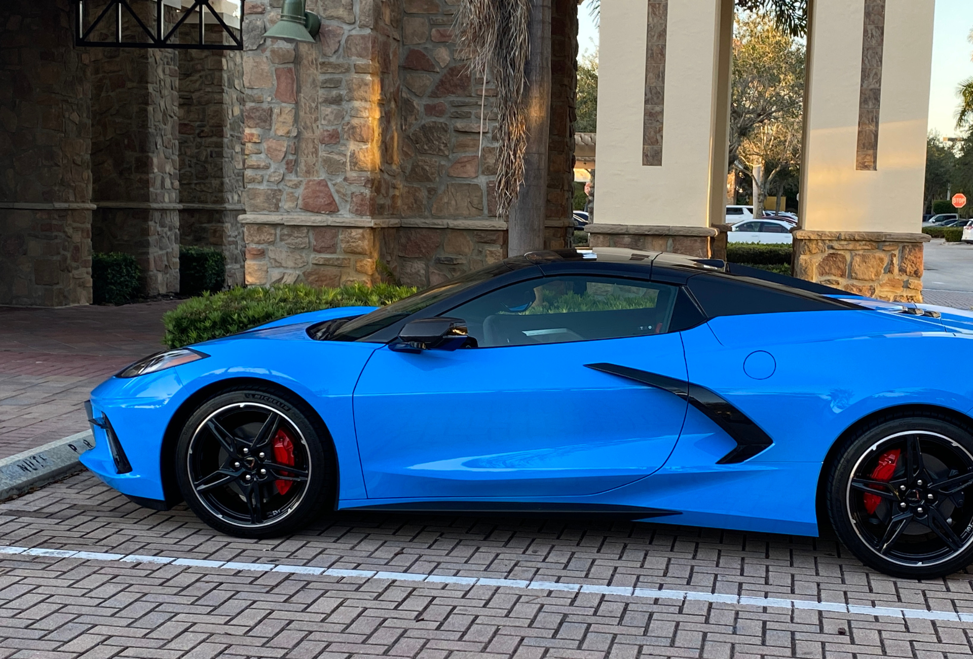 A blue sports car is parked in a parking lot in front of a building.