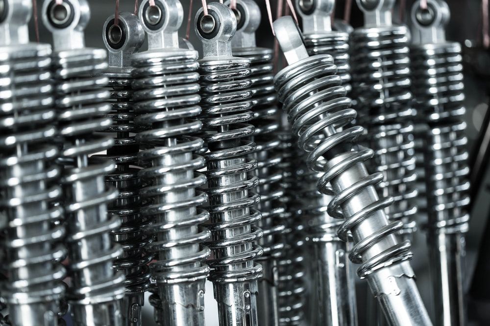 Close-up of a row of shiny metal motorcycle shock absorbers, coiled springs, and silver tubes. — Beenleigh Bearings in Beenleigh, Yatala