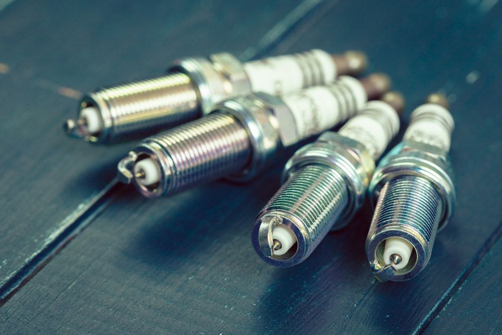 Four silver spark plugs on a blue wooden surface, angled towards the viewer. — Beenleigh Bearings in Beenleigh, Beenleigh