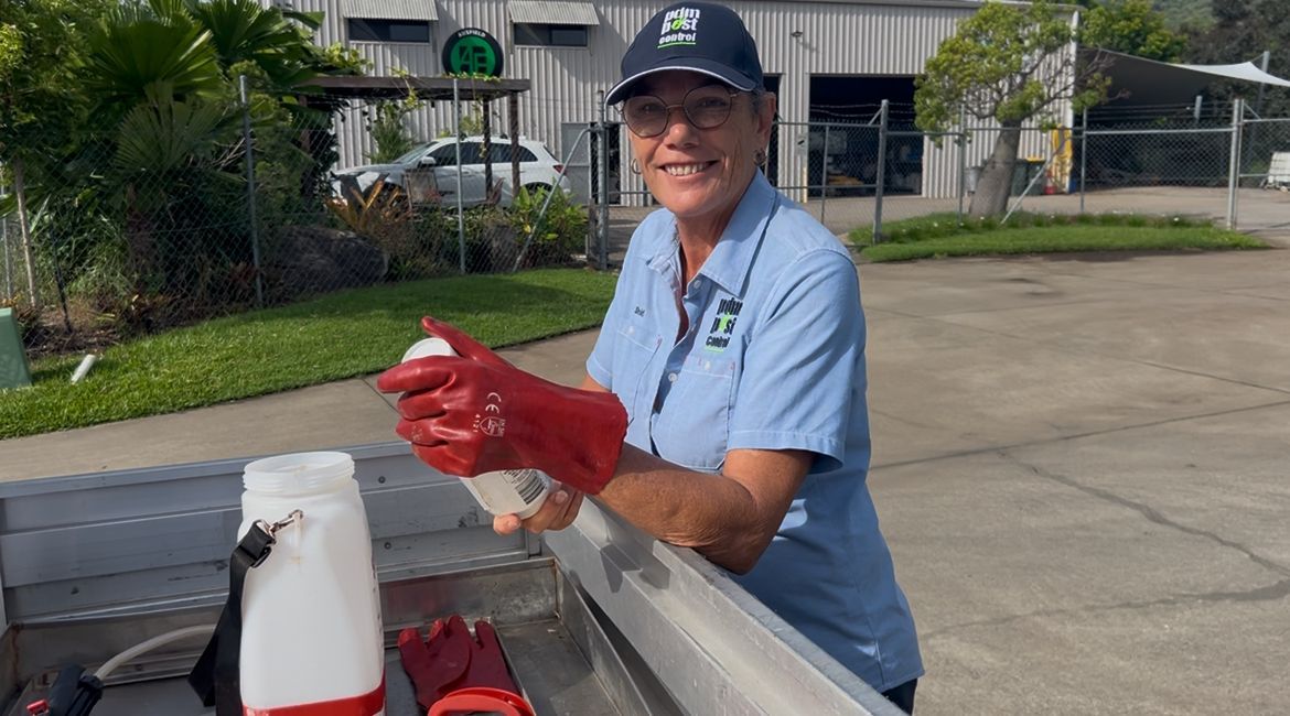 A Man in A Protective Suit Is Spraying a Bottle with A Sprayer — PDM Pest Control in Craiglie, QLD