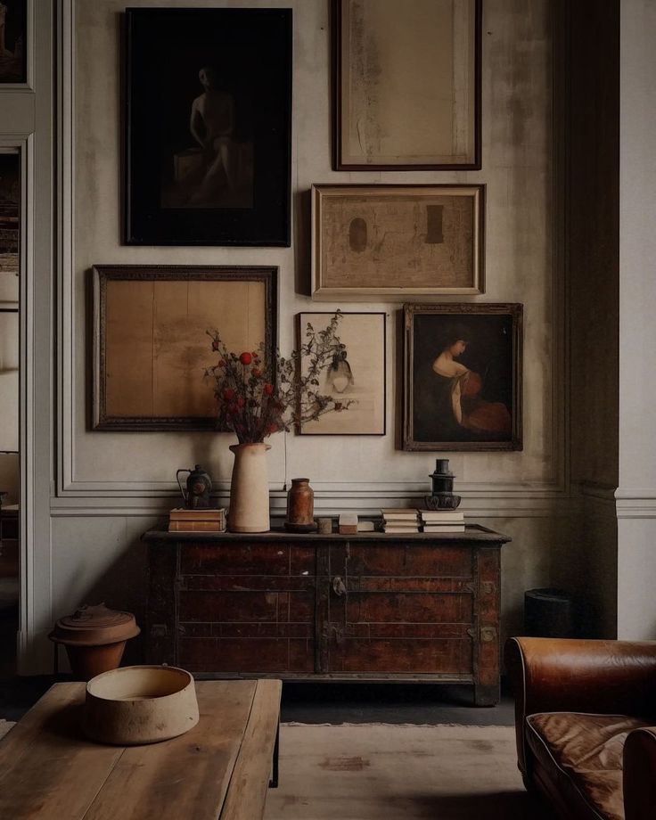 A living room with a dresser and a lot of paintings on the wall.