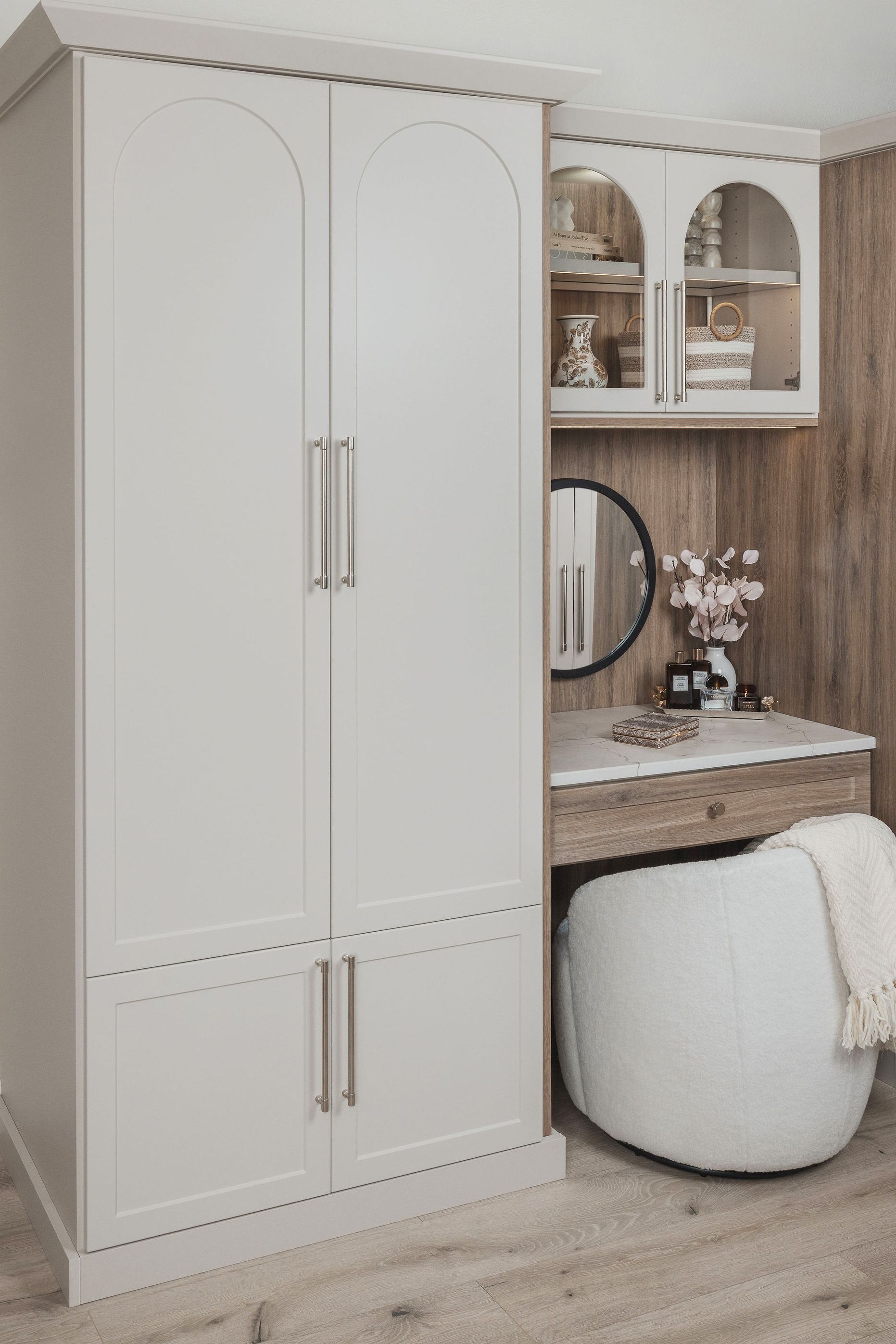 White built-in wardrobe beside a small vanity desk and mirror in a light, cozy bedroom nook