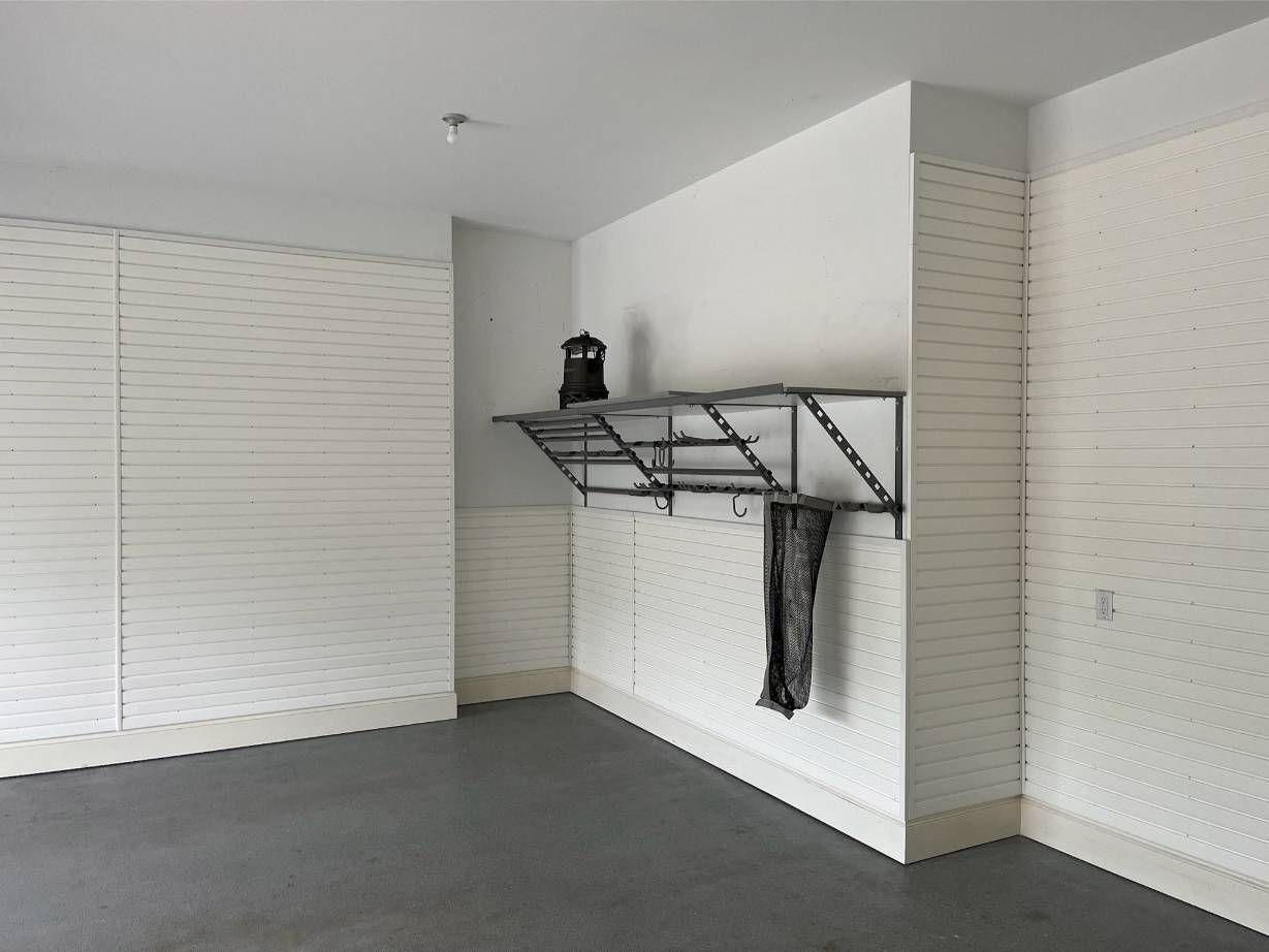 An empty garage with white walls and a shelf on the wall