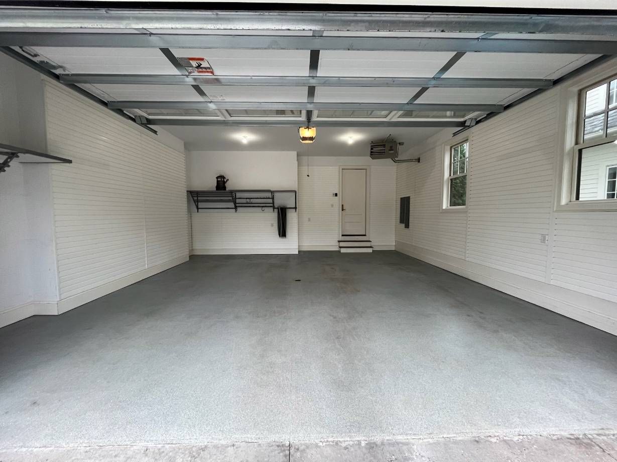 An empty garage with a gray floor and white walls.