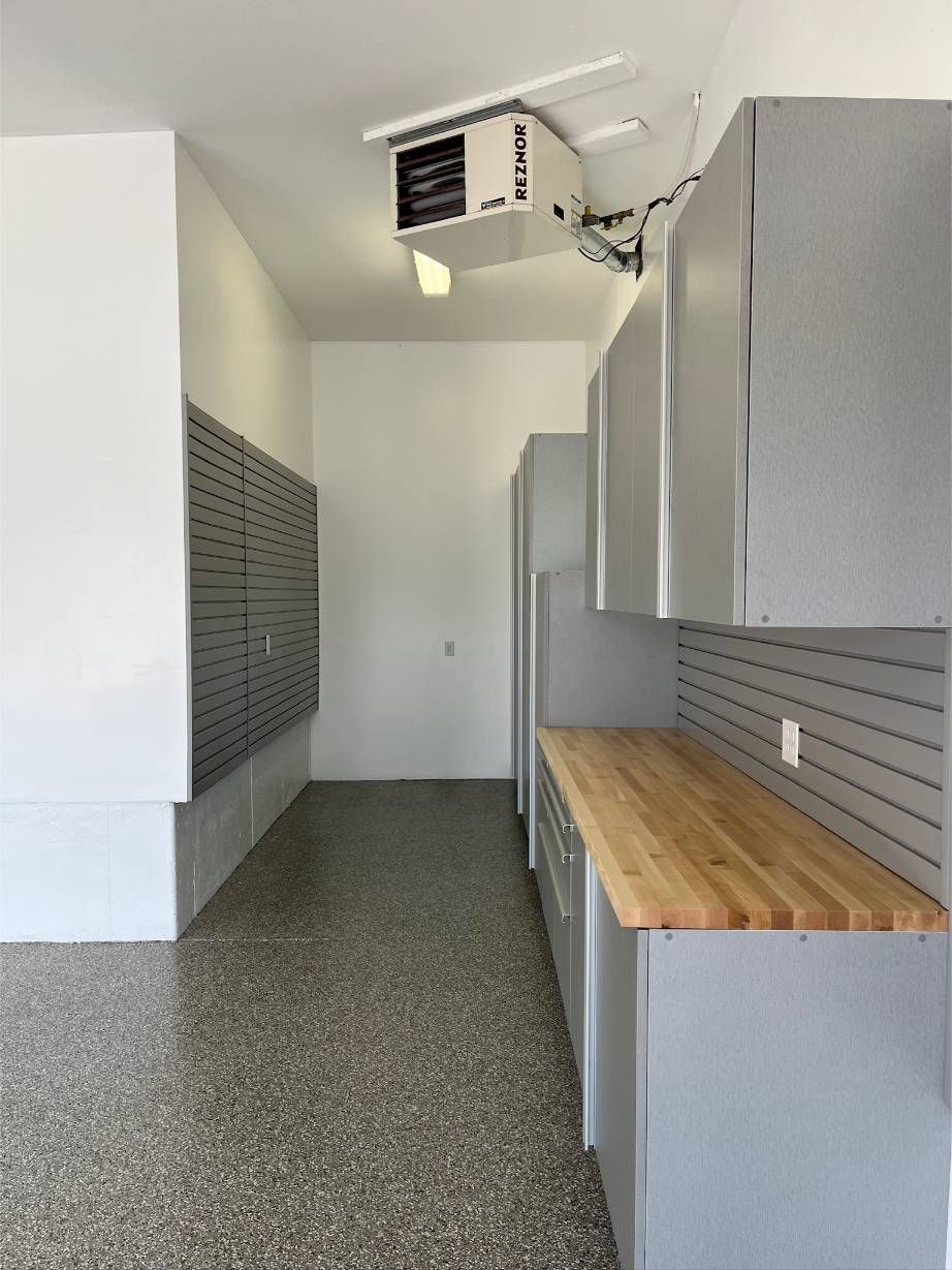 A garage with gray cabinets and a wooden counter top.