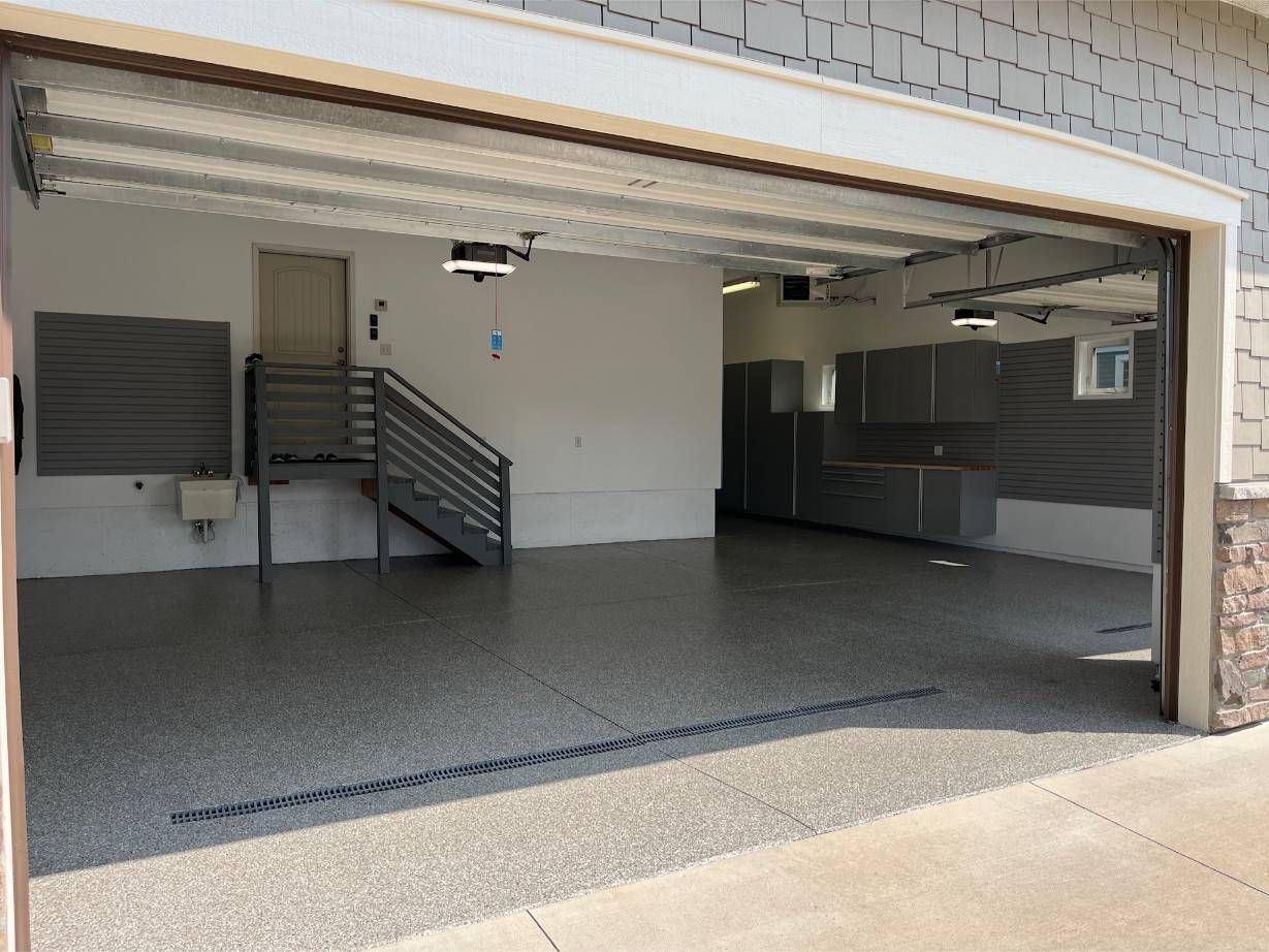 A garage with the door open and a staircase leading up to it.