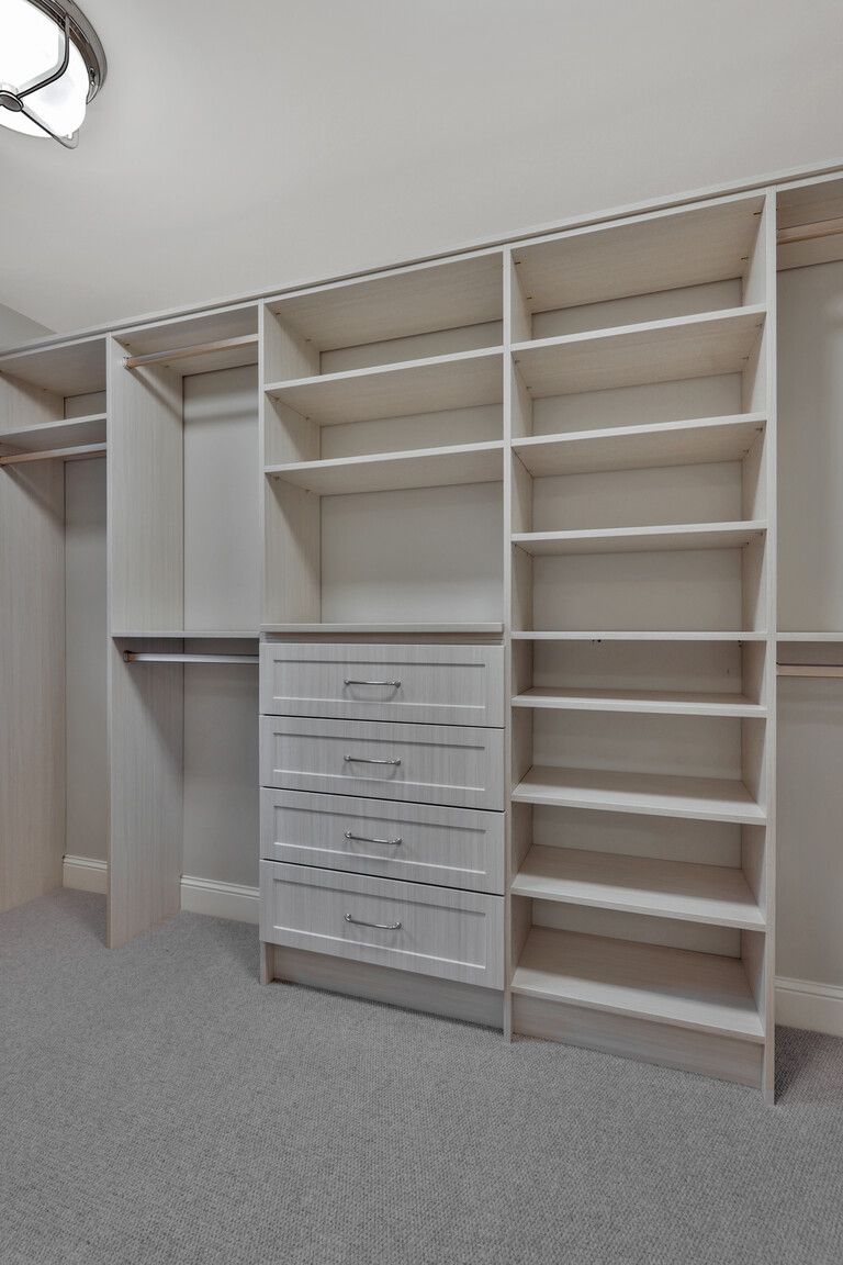 A walk in closet with lots of shelves and drawers.