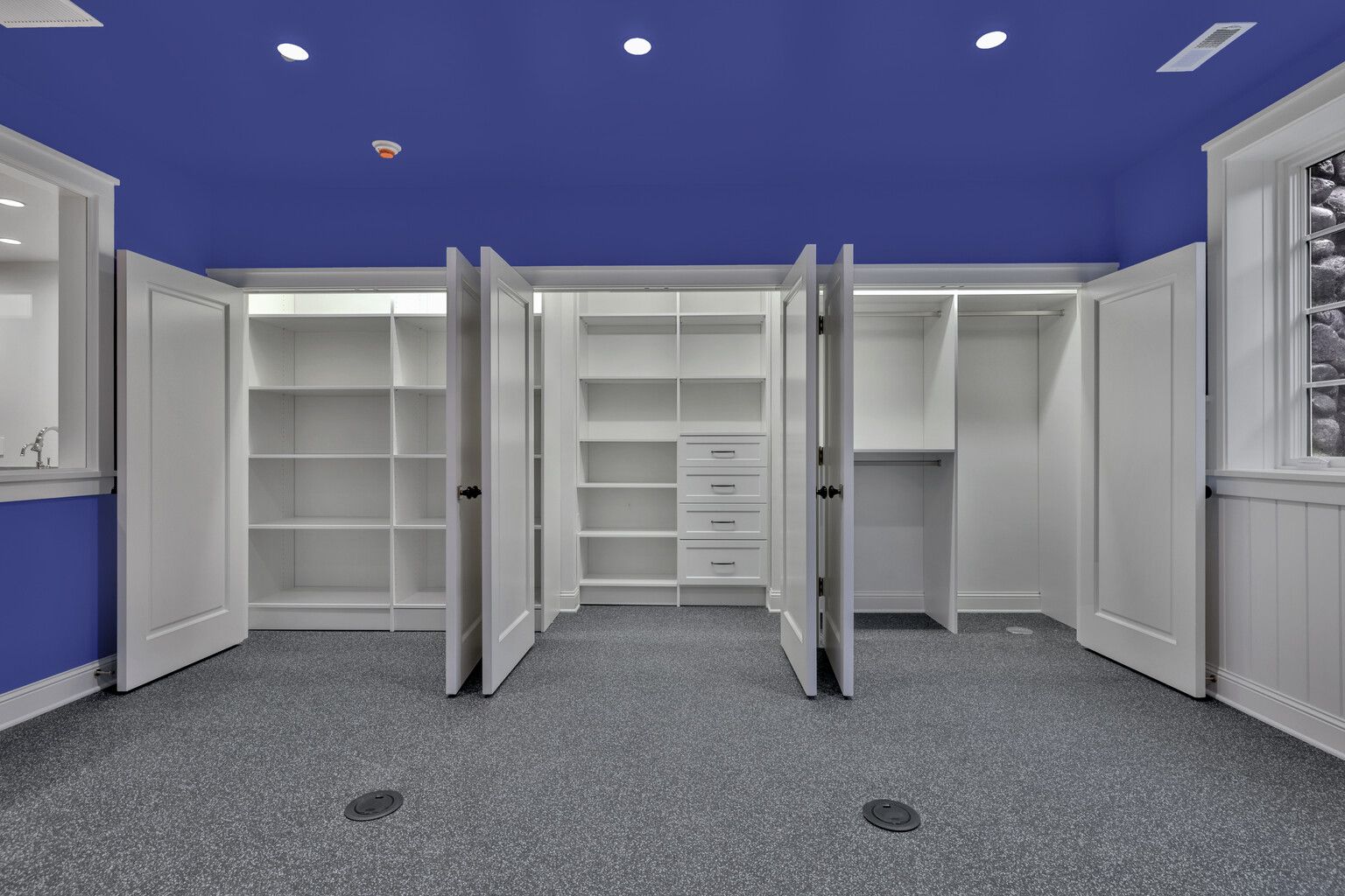 A room with a blue ceiling and white shelves and doors.