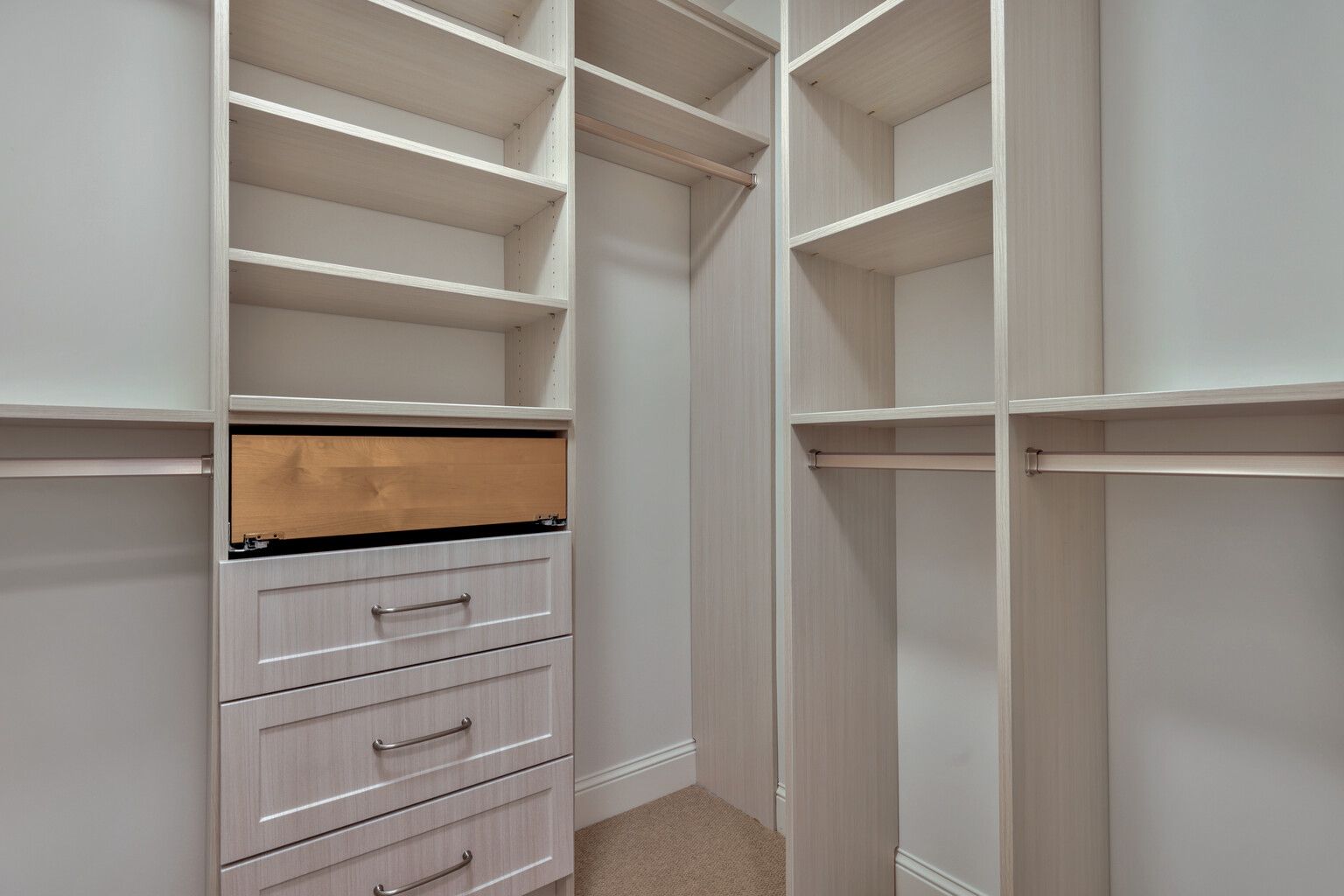 A walk in closet with lots of shelves and drawers.